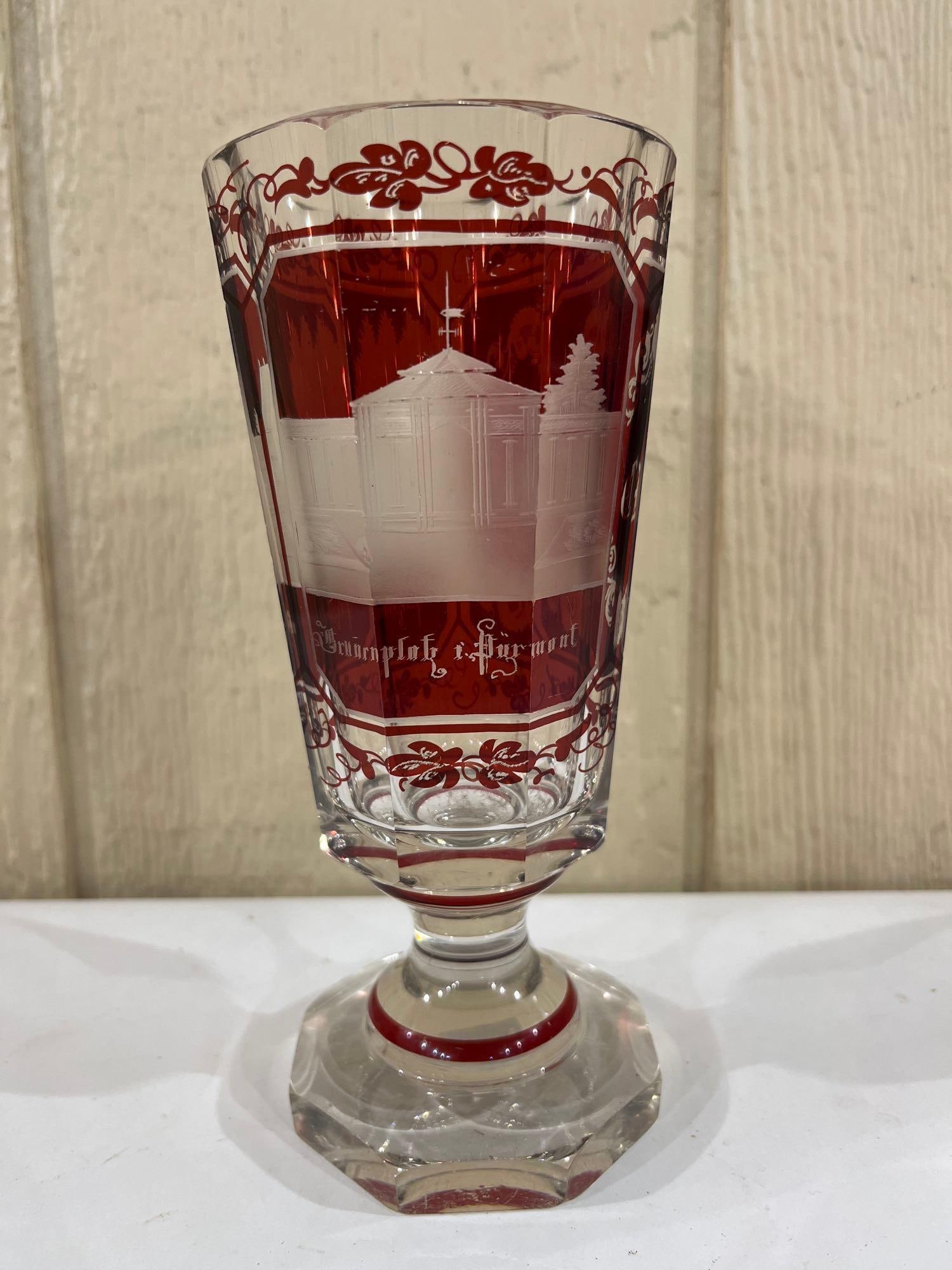 Bohemian Ruby Cut Spa Glass, Pyrmont & Bad Altenau: This footed spa glass, also known as a Kurglas, is constructed from clear lead crystal with ruby red staining that has been cut-to-clear. The vessel features an octagonal faceted body and a matching