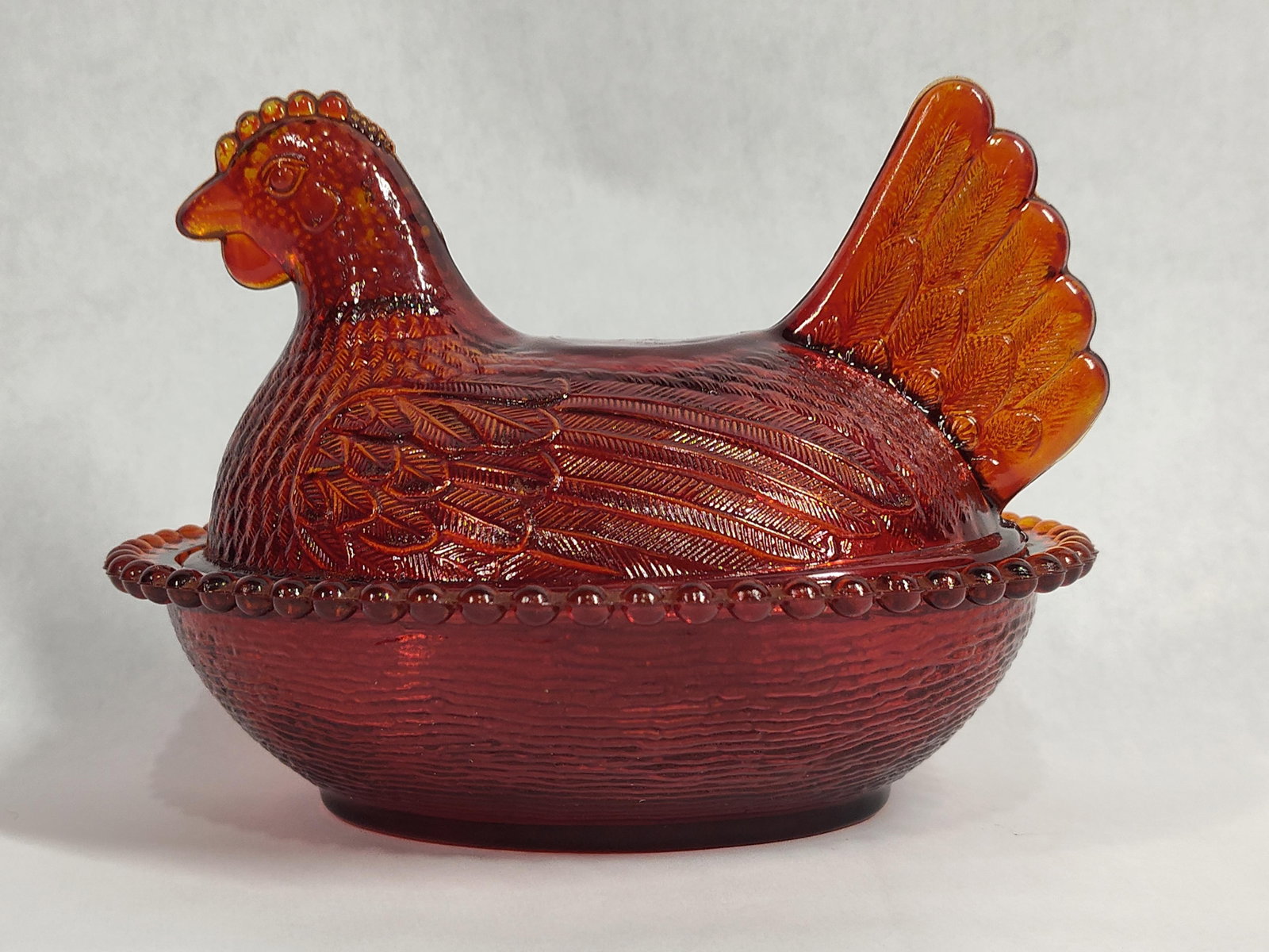 Indiana Glass Amberina Hen on Nest Beaded Rim Dish: This pressed glass covered dish is designed in the classic Hen on Nest form, attributed to the Indiana Glass Company. The piece is rendered in Amberina glass, which exhibits a graded color transition