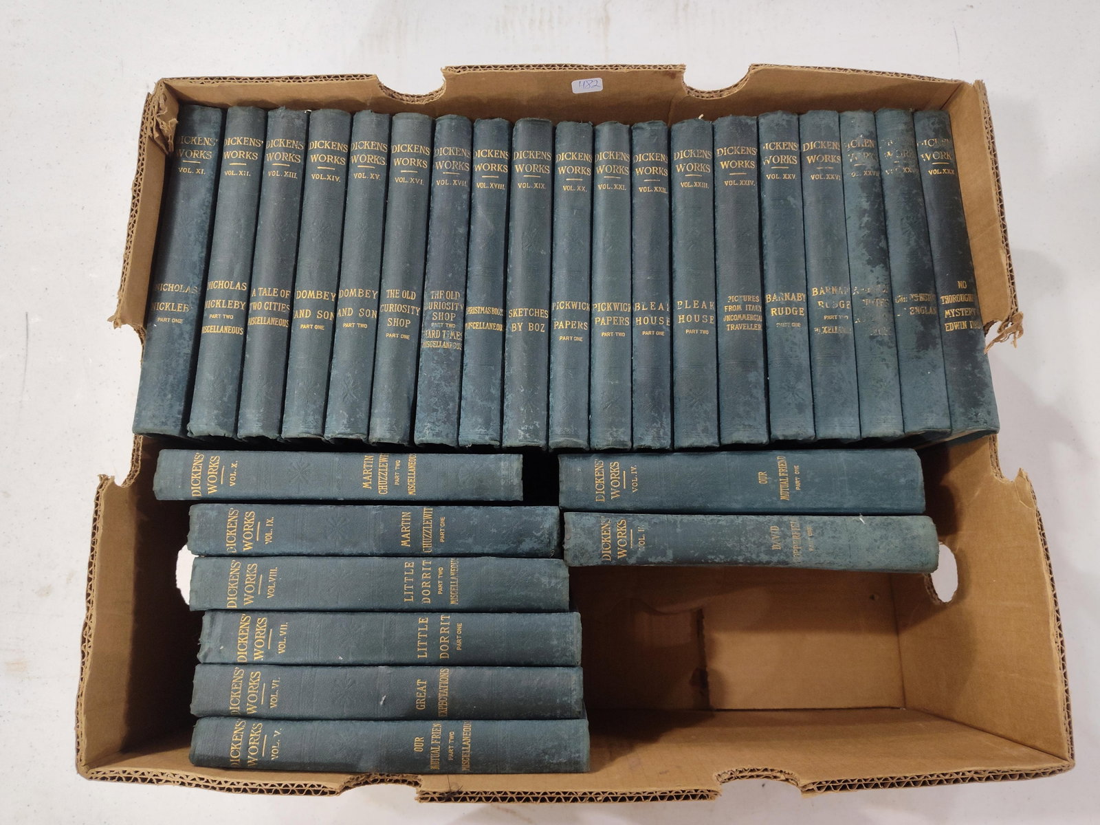 Charles Dickens, Works, Set, c. 1890-1910: A collection of hardcover volumes comprising the works of Charles Dickens. The books are bound in textured dark blue cloth with gilt lettering and volume numbering on the spines. The titles visible