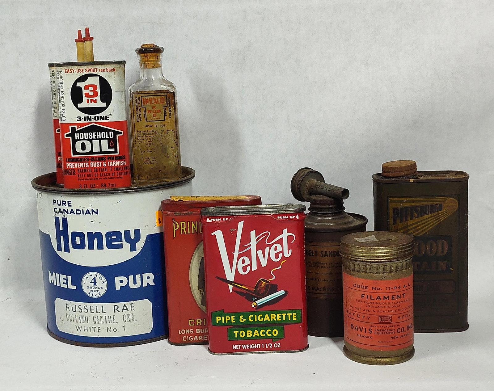 Vtg Lithographed Advertising Tins & Containers: This collection of mid-twentieth-century advertising containers includes various lithographed tins and one glass bottle. The group features a Russell Rae Pure Canadian Honey tin from Holland Centre,