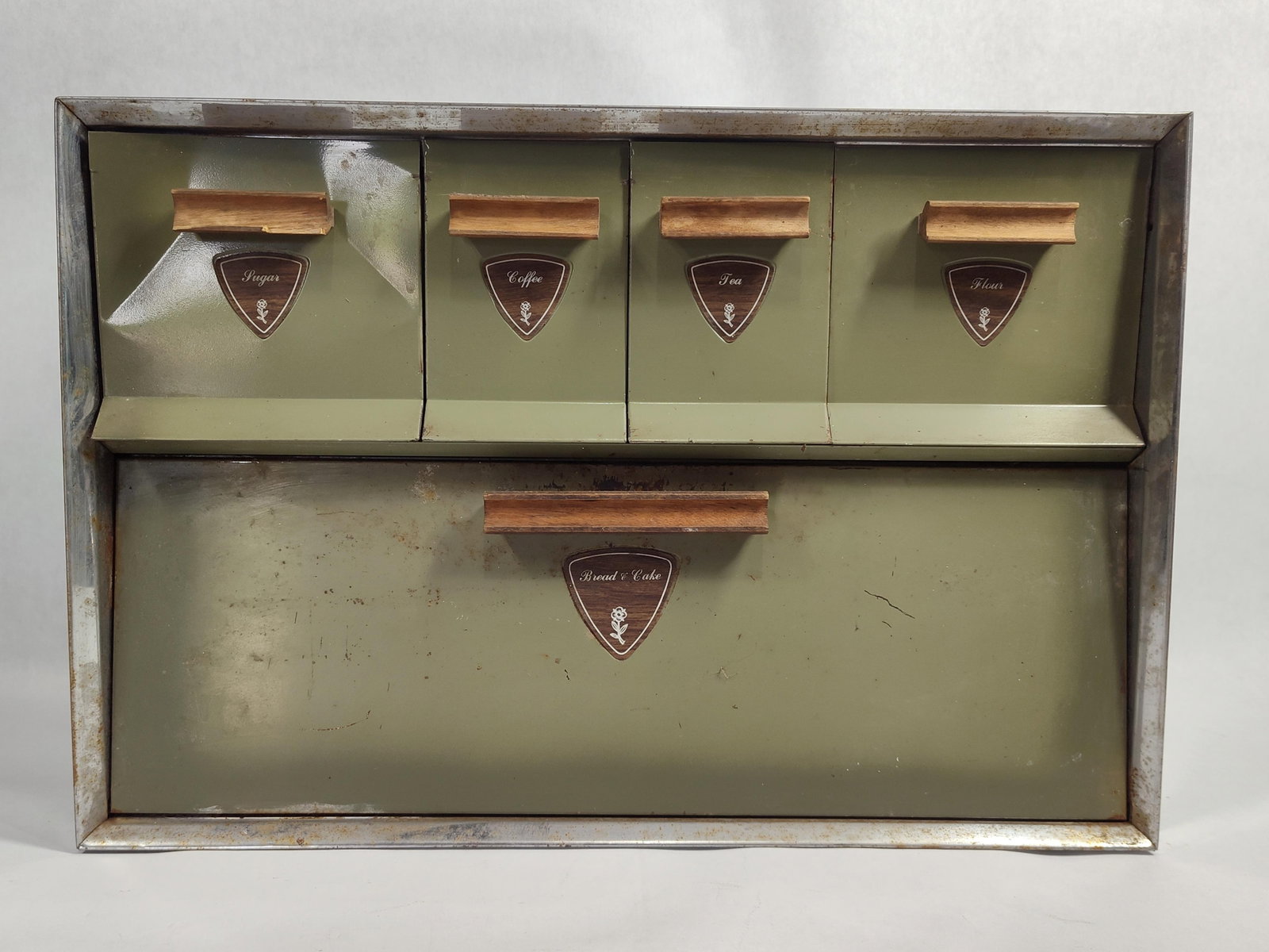Avocado Green Metal Bread Box & Tilt-Out Canisters: This vintage kitchen countertop storage unit is a combination bread box and four-canister set, constructed from sheet metal with chrome-plated trim. The exterior is finished in avocado green paint.