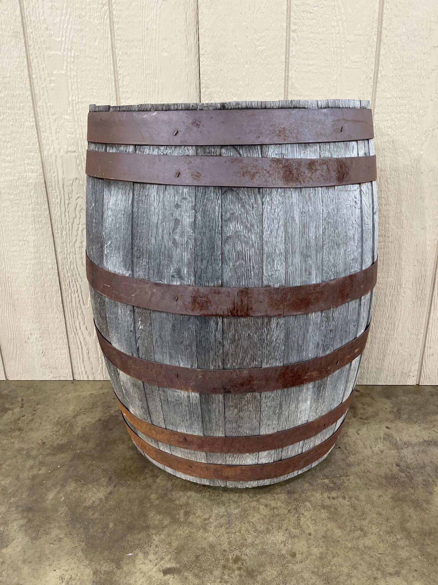 Repurposed Half-Barrel Wall Shelf w/ 2 Tiers: A wall-mounted shelving unit constructed from a repurposed half-barrel. The piece features a curved front and a flat back for flush mounting. It is composed of weathered wood staves secured by