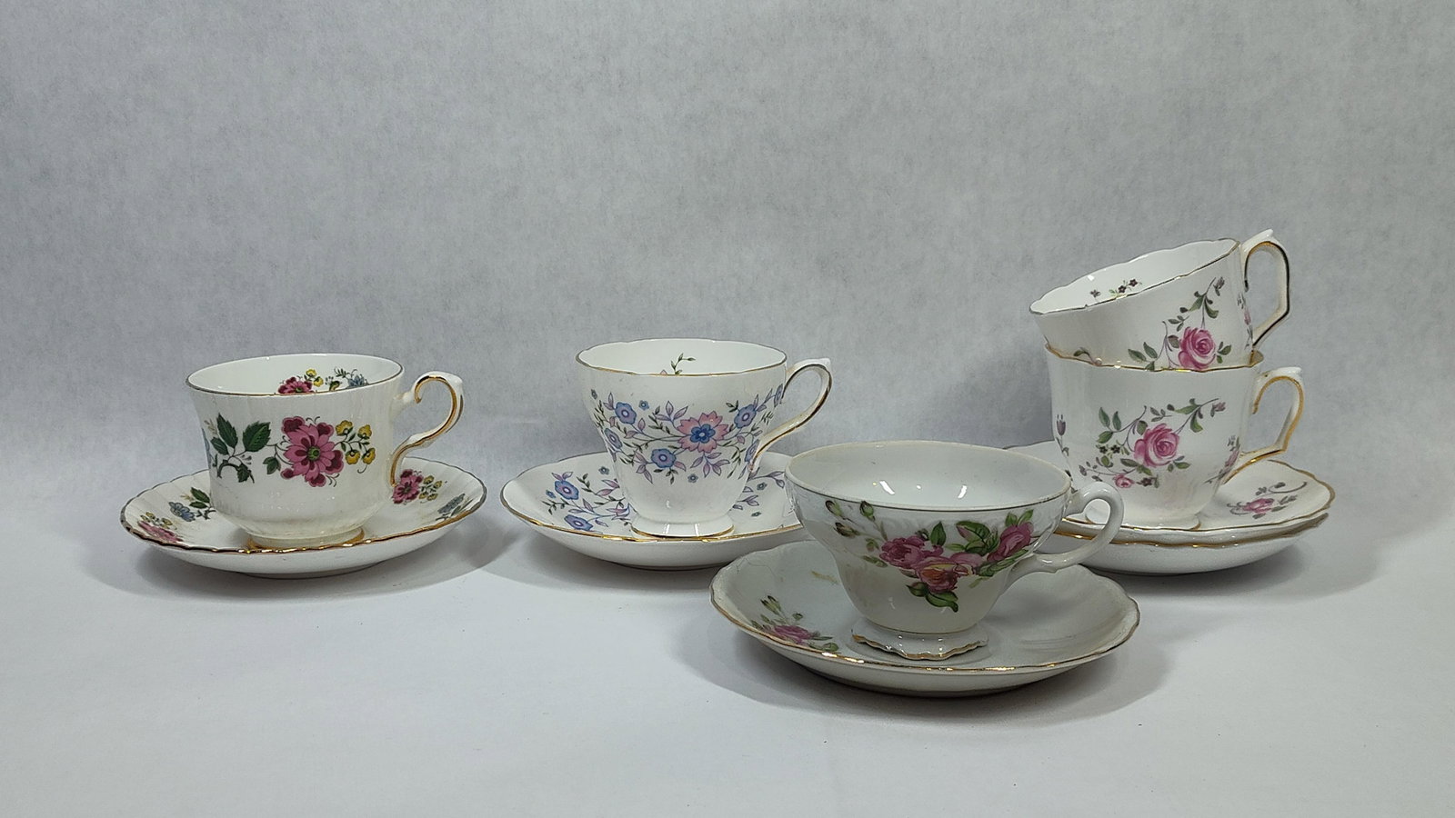 Set 5 Vtg Porc. Floral Teacups & Saucers: This collection consists of five teacups and five matching saucers, totaling ten pieces, crafted from fine porcelain. The set features a variety of traditional mid-20th-century forms, including