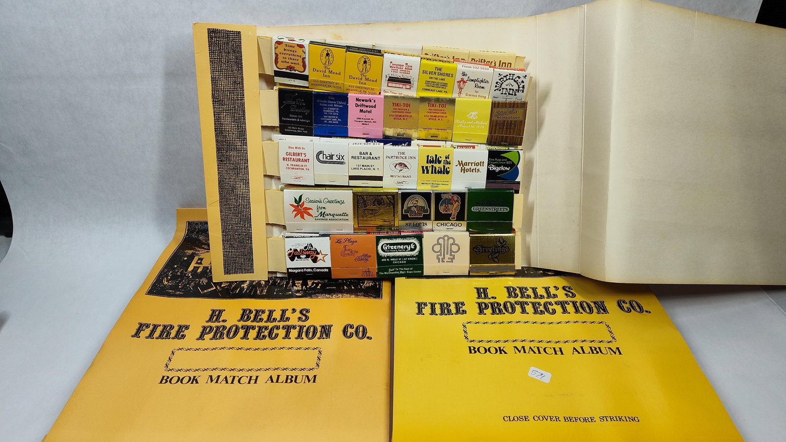 Vtg H. Bell's Fire Protection Co. Matchbook Covers: A collection of vintage matchbook covers from the mid-to-late 20th century, organized within two specialized storage albums. The albums are constructed of yellow cardstock and are printed with the