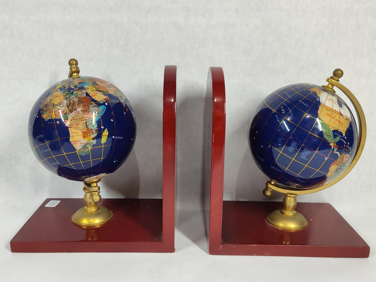 Pair Gemstone Inlay World Globe Bookends, Wood: A pair of decorative bookends featuring world globes with a dark blue lapis-toned ground. The globes are detailed with multi-colored semi-precious gemstone inlays, including various stones used to