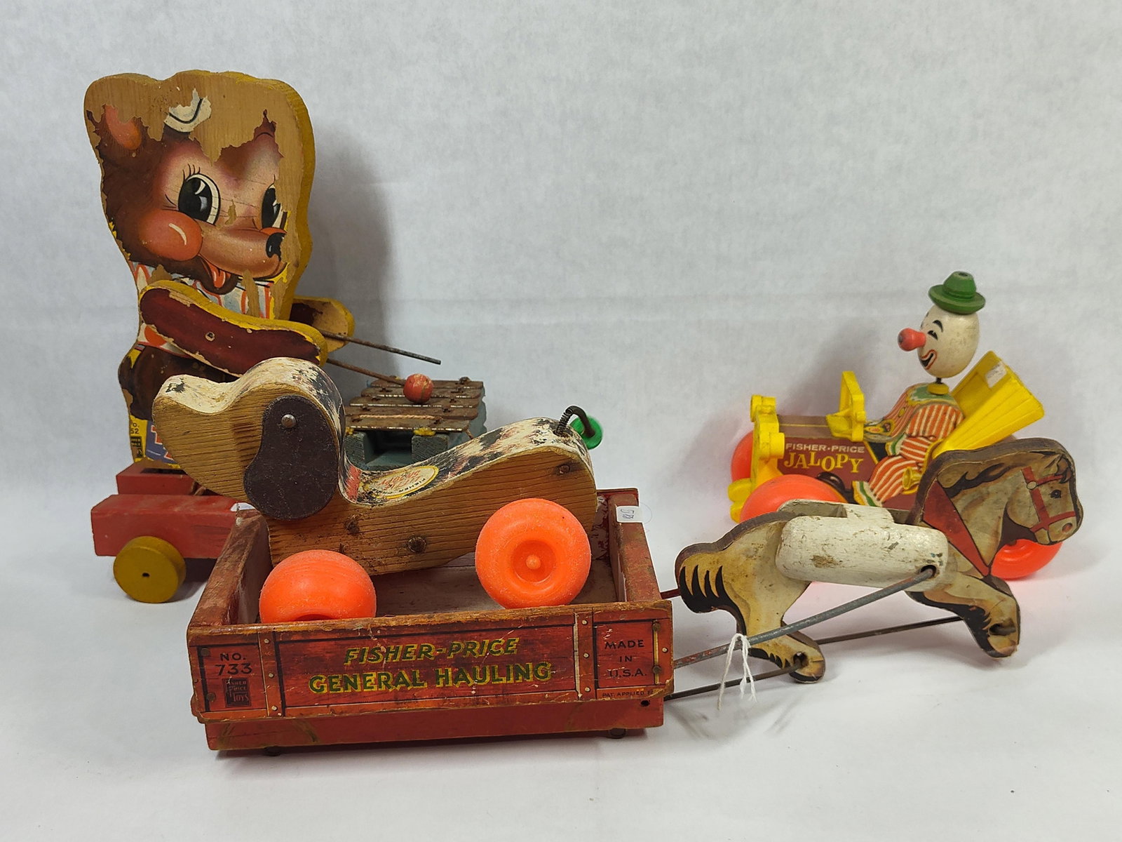 Fisher-Price Wood & Paper Lithography Pull Toys: This collection features several vintage pull toys manufactured by Fisher-Price Toys in the United States. The items are primarily constructed from wood with applied paper lithography, alongside plast