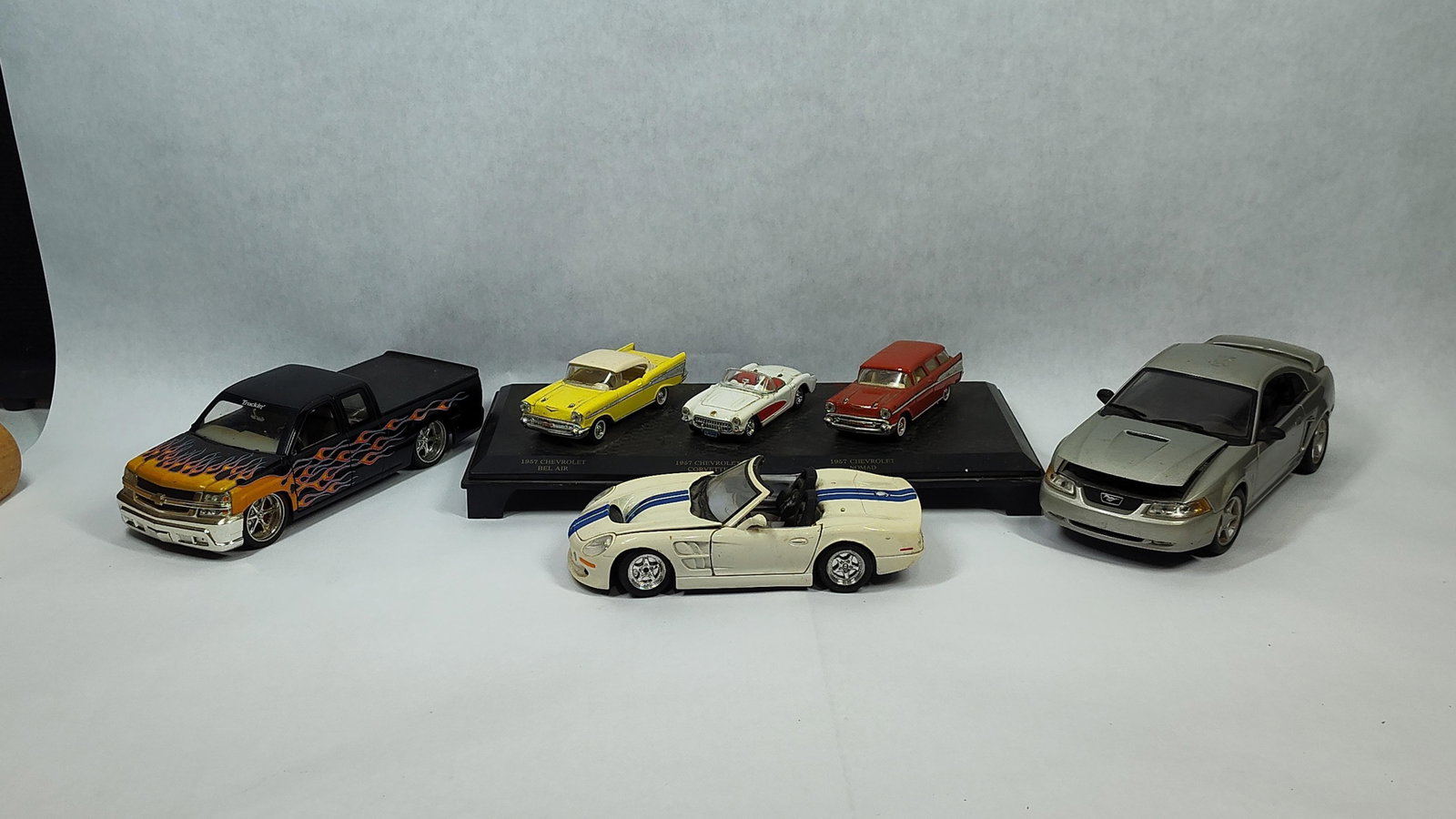 5 Die-Cast Models w/ 1957 Chevrolet Trio & Custom: A collection of five die-cast model vehicles featuring a mix of vintage and modern styles. The group includes a three-car display set of 1957 Chevrolet models mounted to a black plastic plinth,