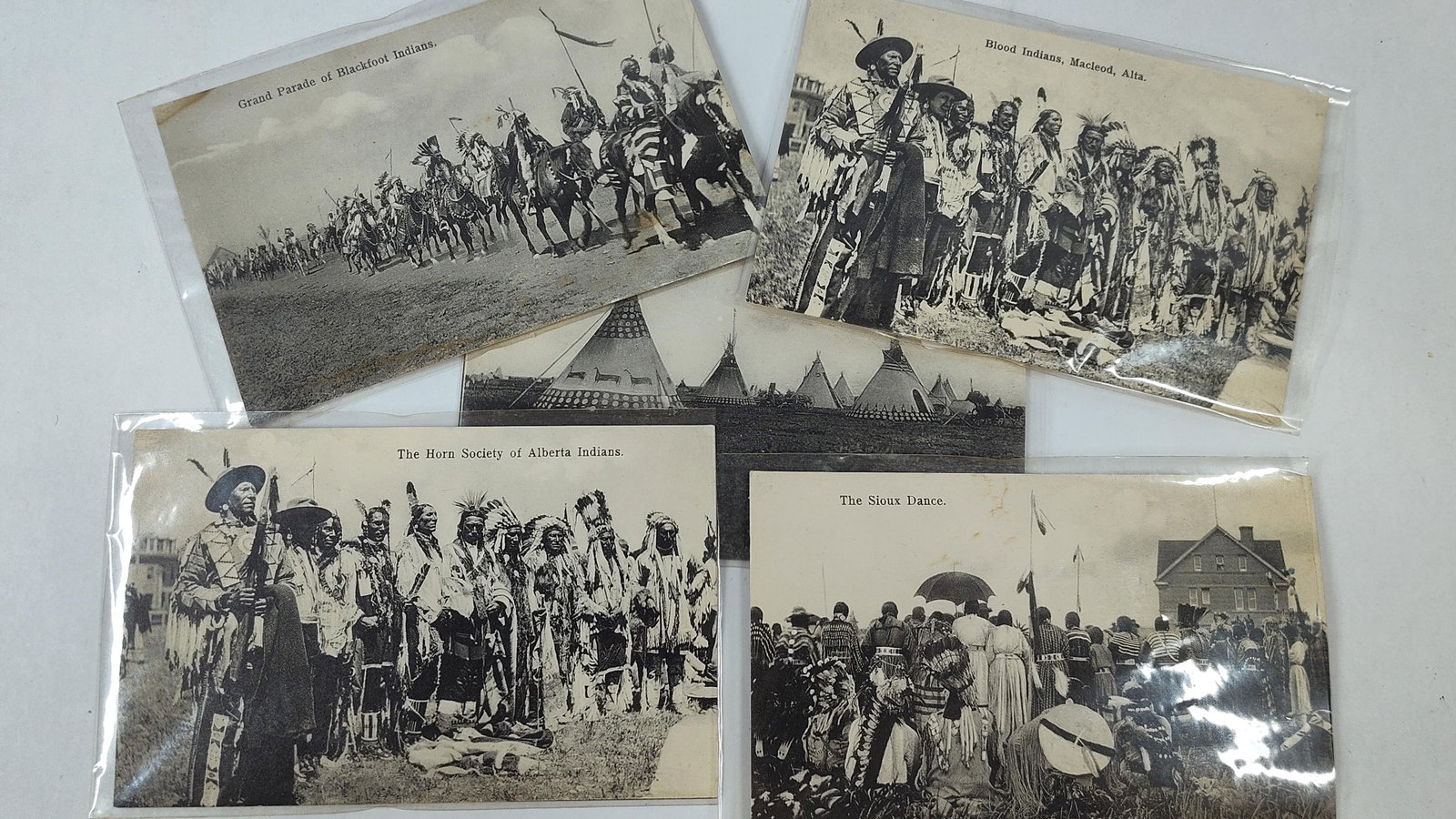 A. Young & Co. 1907 Alberta Indigenous Postcards: A collection of five vintage black and white postcards depicting Indigenous peoples and encampments in Alberta, Canada, circa 1907. This group includes specific scenes titled Grand Parade of