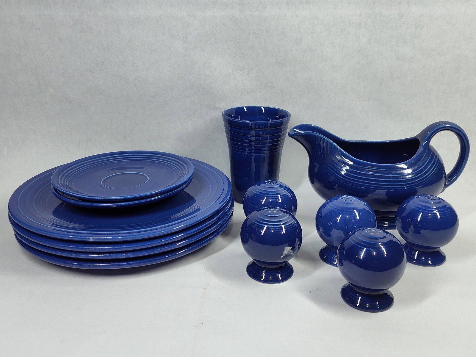 13 Homer Laughlin Style Cobalt Blue Tableware: This collection of thirteen cobalt blue glazed earthenware tableware pieces is designed in the style of the Fiesta line by Homer Laughlin China Co. The grouping includes four dinner plates with