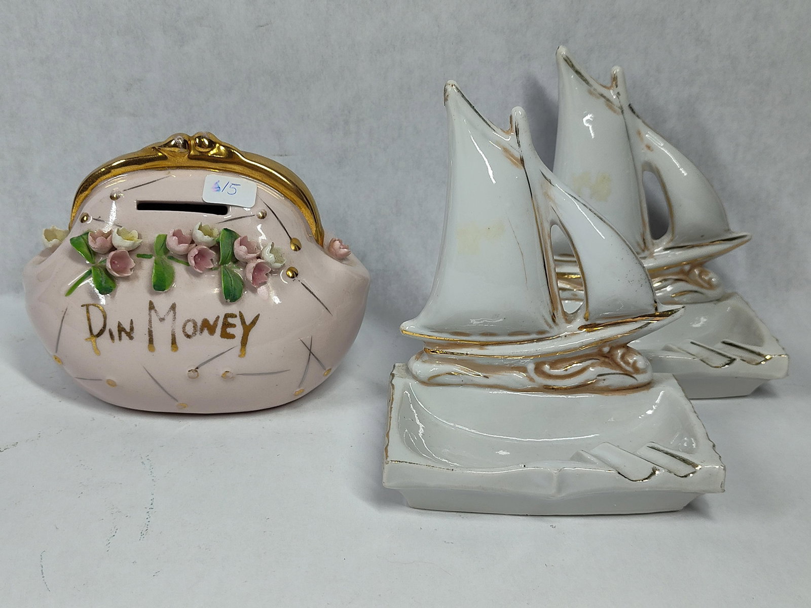 Mid-C. Lofton China Bank & 2 Sailboat Ashtrays: This lot features a mid-century Lofton China Pin Money coin bank and a matching pair of sailboat-themed ashtrays. The coin bank is modeled in the form of a frame-top lady's handbag with a pink glazed
