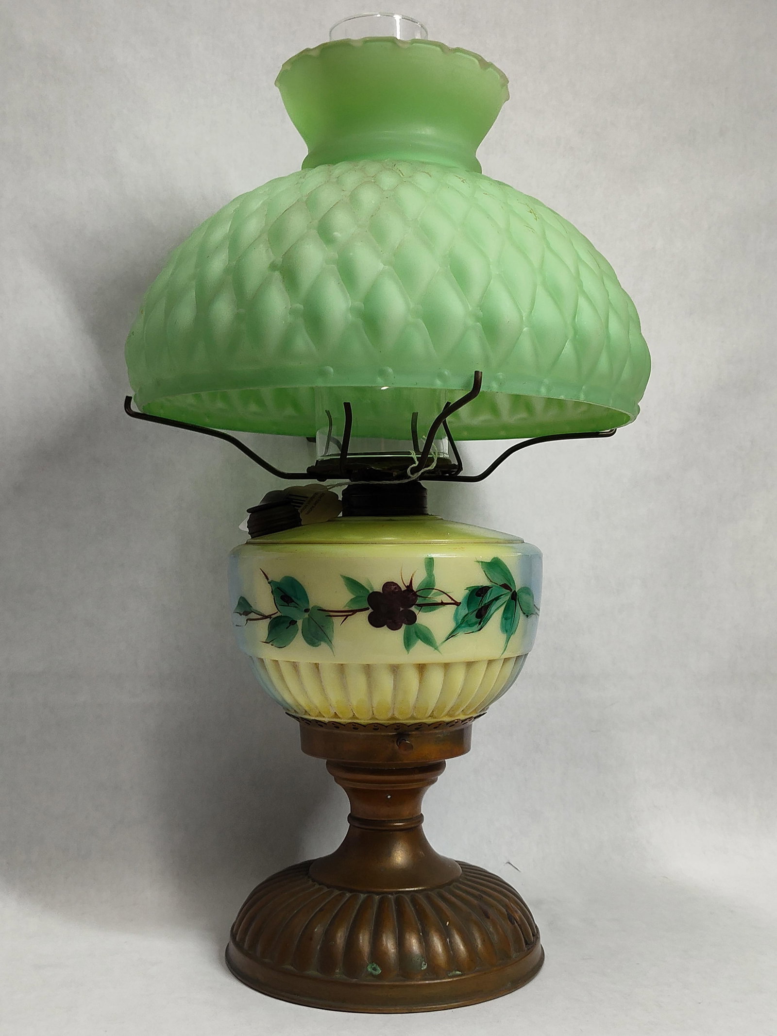 Victorian Style Oil Lamp w/ Green Quilted Glass: This composite oil lamp features a mold-blown green satin glass shade with a diamond-quilted pattern and a crimped or ruffled upper rim. The shade sits above a clear glass chimney and metal burner