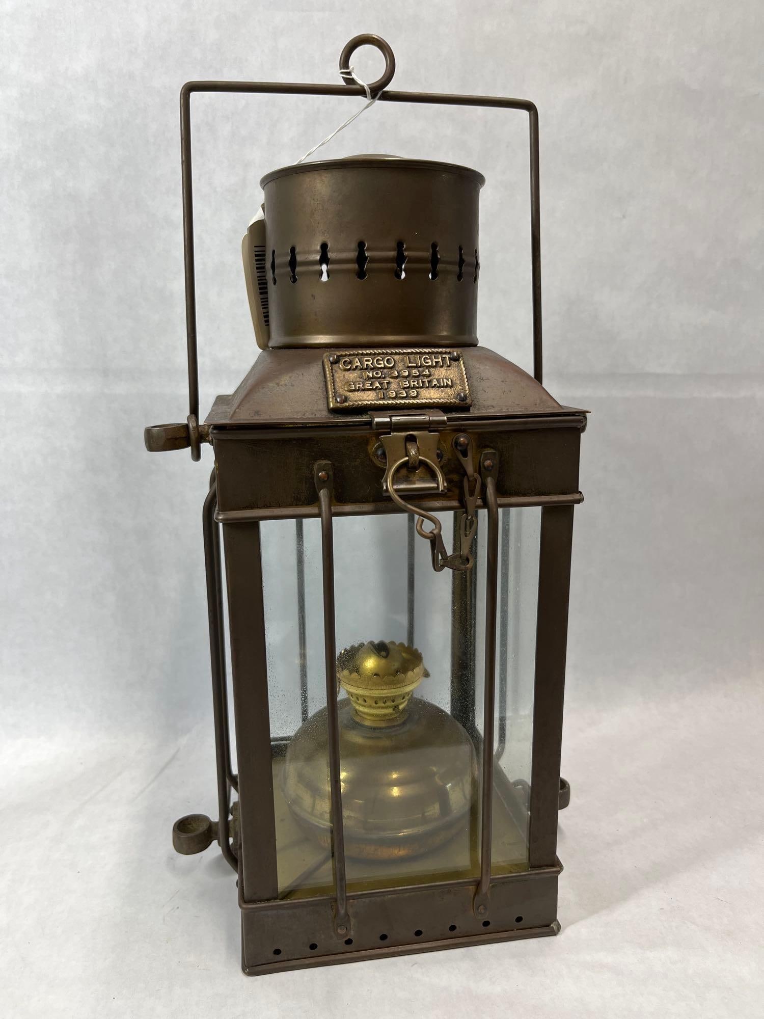 British WWII Brass Maritime Cargo Lantern, 1939: This maritime cargo lantern, identified as Cargo Light No. 3954, is a piece of British shipboard equipment from the early World War II period. The lantern is constructed with a rectangular brass
