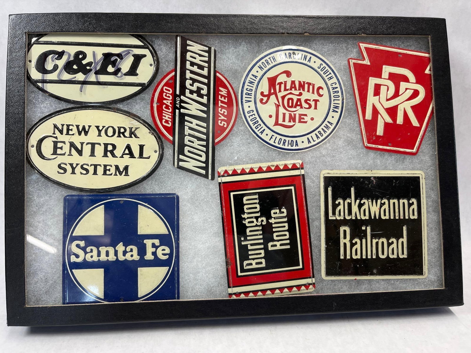 Set 8 Porc. Enamel Railroad Herald Signs: A collection of eight miniature porcelain enamel signs representing historic American railroads, presented in a professional black wooden shadowbox display. The set includes the heralds of the