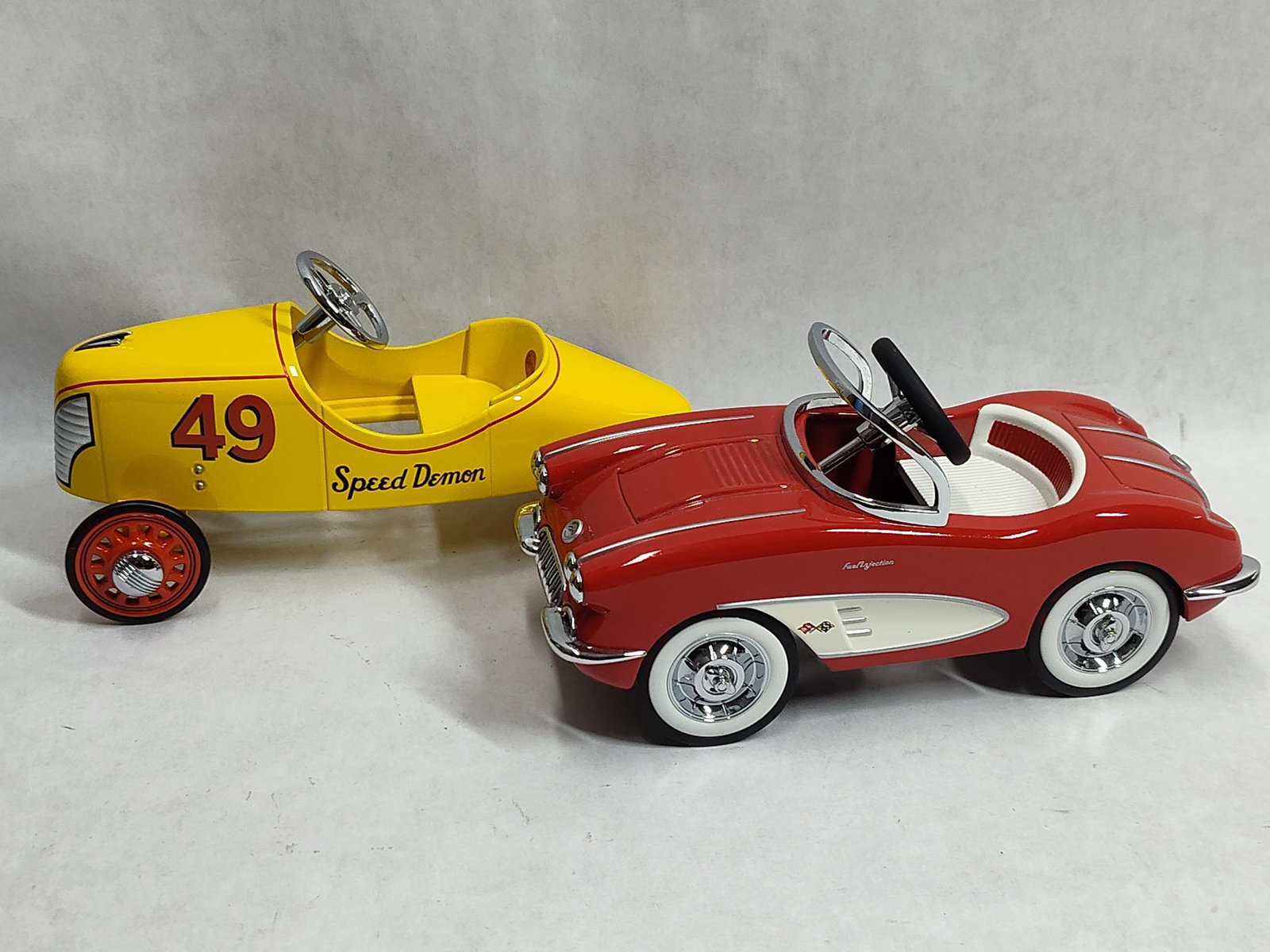 Pair Hallmark Kiddie Car Classics Metal Pedal Cars: This lot consists of two metal scale models from the Hallmark Kiddie Car Classics collection, designed as replicas of pedal cars. The first model is a yellow Garton Speed Demon racer featuring red