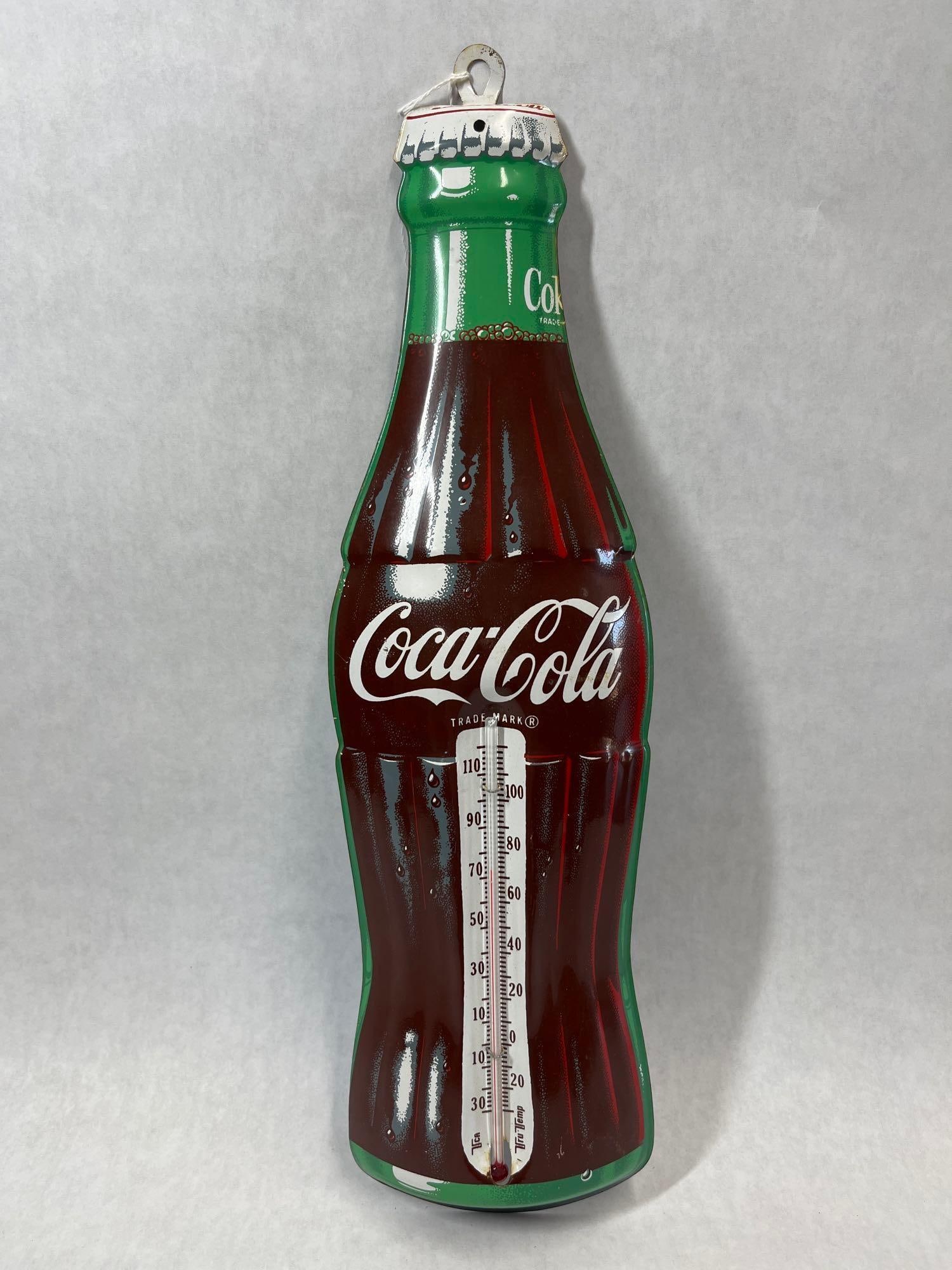 TCA Tru-Temp Coca-Cola Bottle-Shaped Thermometer: This is a Coca-Cola promotional wall thermometer constructed from die-cut lithographed tin in the shape of a contour glass bottle. The sign features realistic graphics of a full beverage bottle with