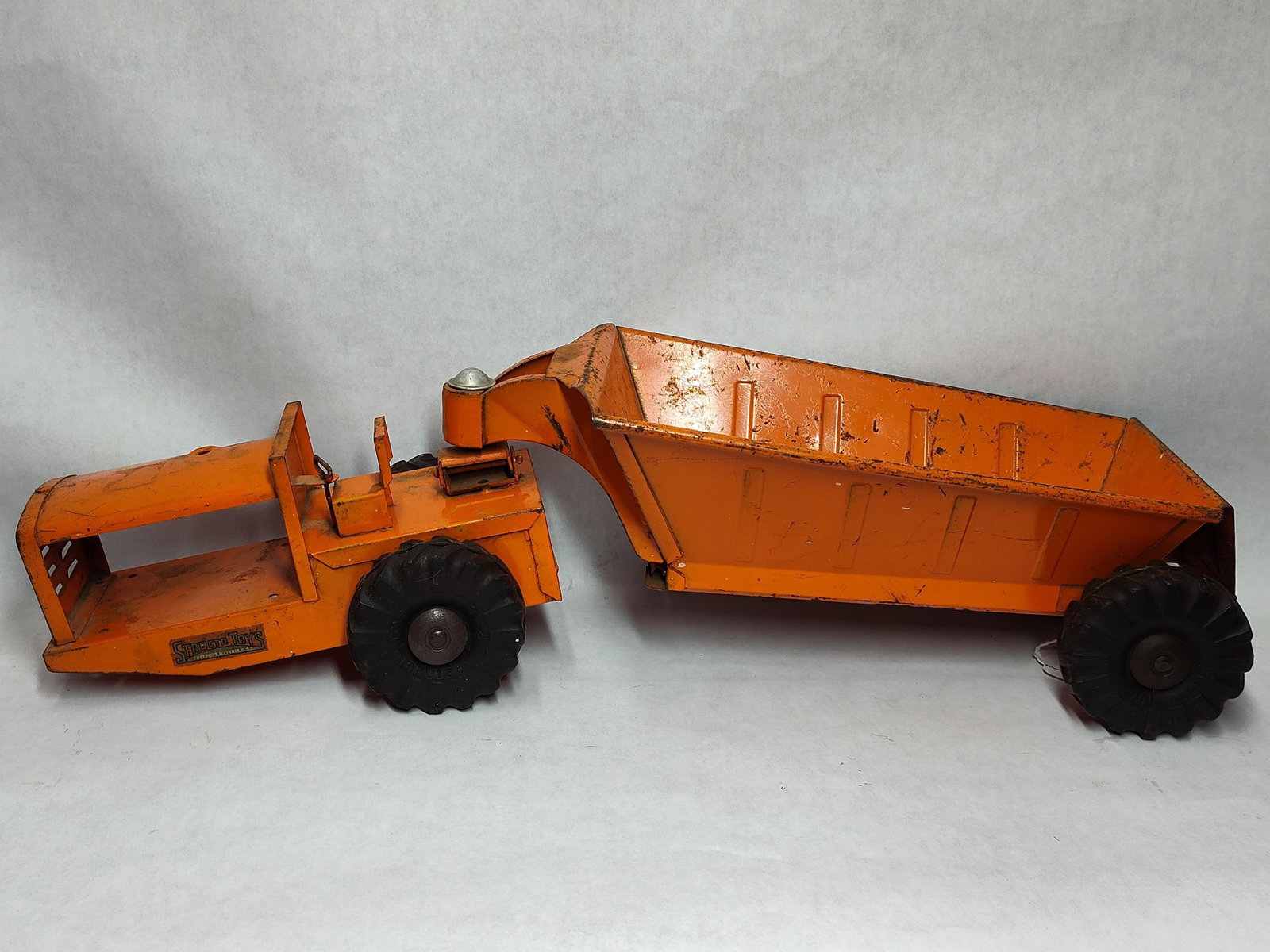 1950s Structo Toys Articulated Bottom Dump Earth Mover No. 320: This mid-century construction toy is an articulated bottom dump earth mover manufactured by Structo Toys of Freeport, Illinois. The vehicle is constructed of pressed steel and finished in orange