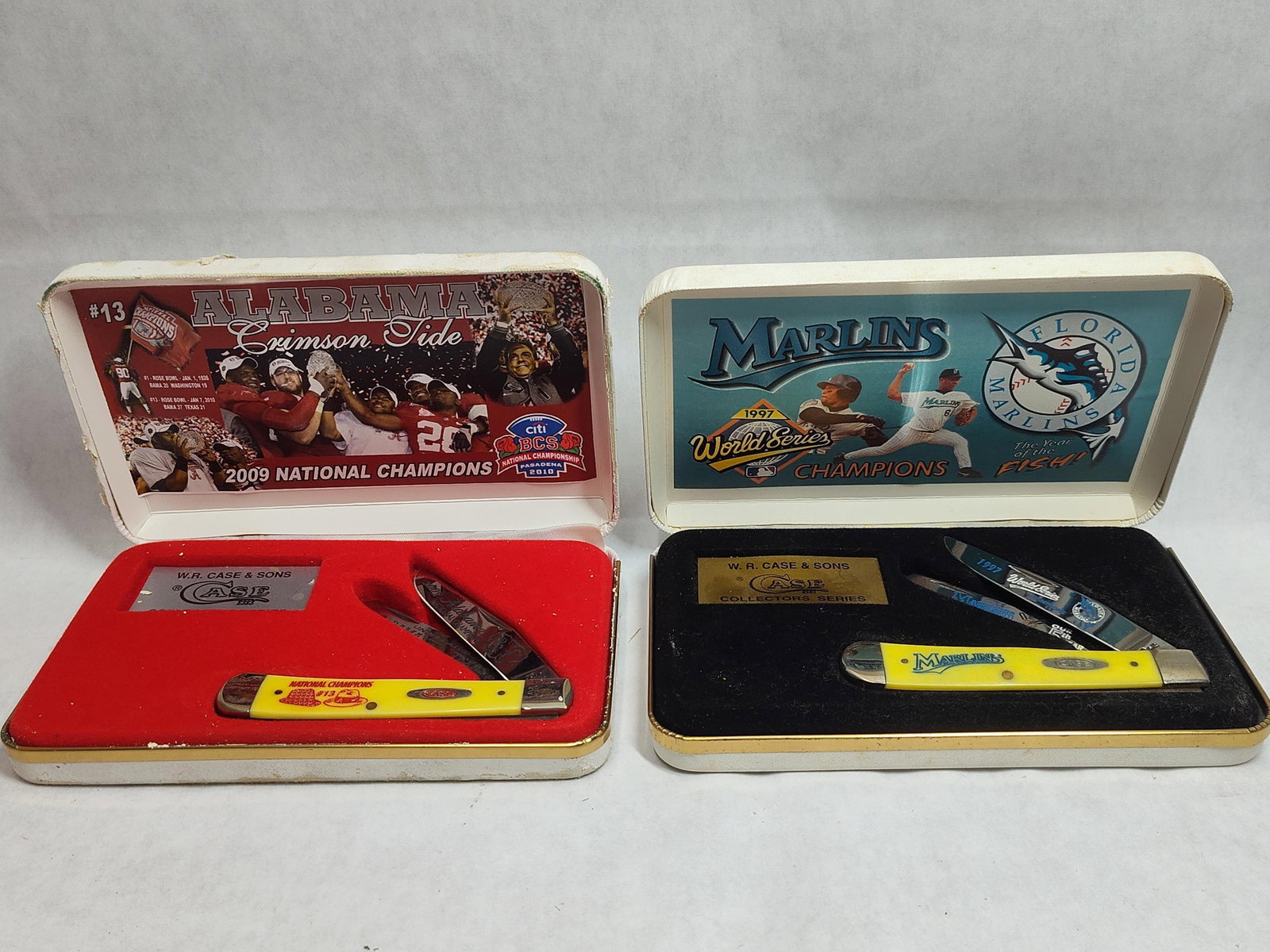 Pair Case XX Trapper Knives: AL & FL Marlins Champ: This lot features two commemorative trapper-style folding knives manufactured by W.R. Case and Sons. Each knife is constructed with two stainless steel blades, yellow synthetic handle scales, and