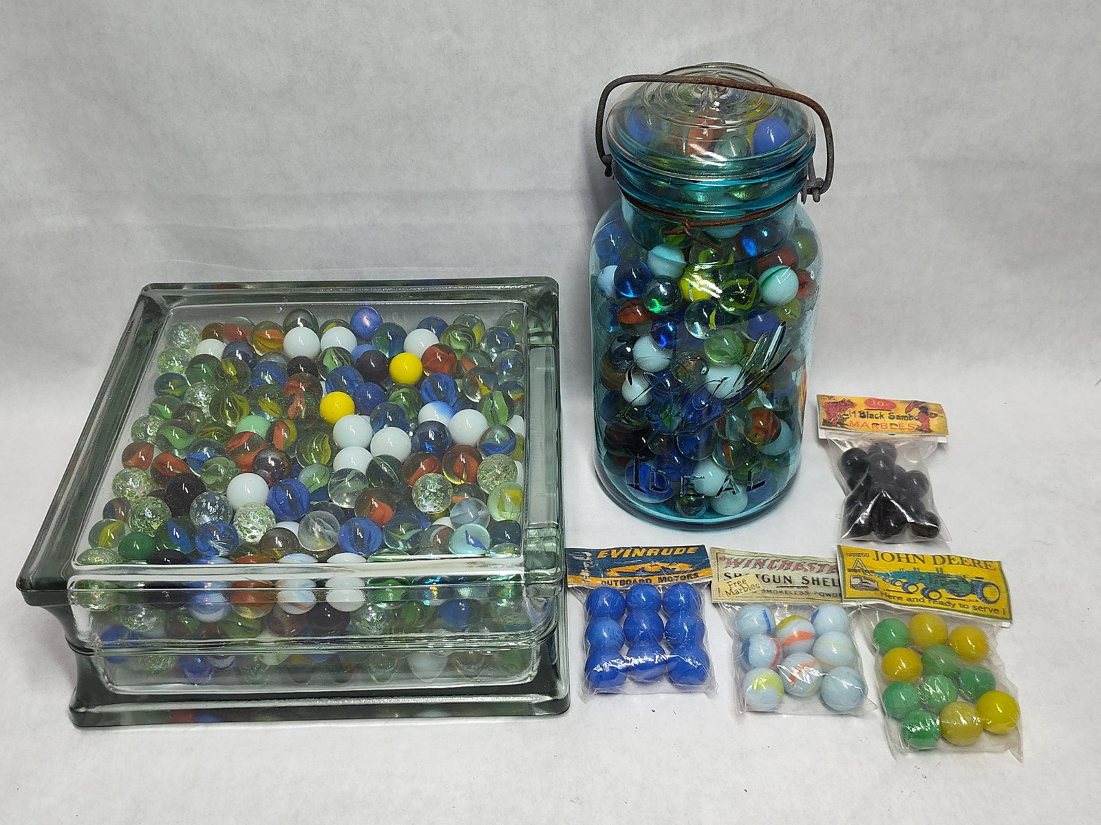 & Collectible Marbles w/ Promotional Bags: A large collection of marbles in various styles, sizes, and colors, including two primary storage containers and several promotional novelty bags. The assortment includes cat s eyes, swirls, solid opa