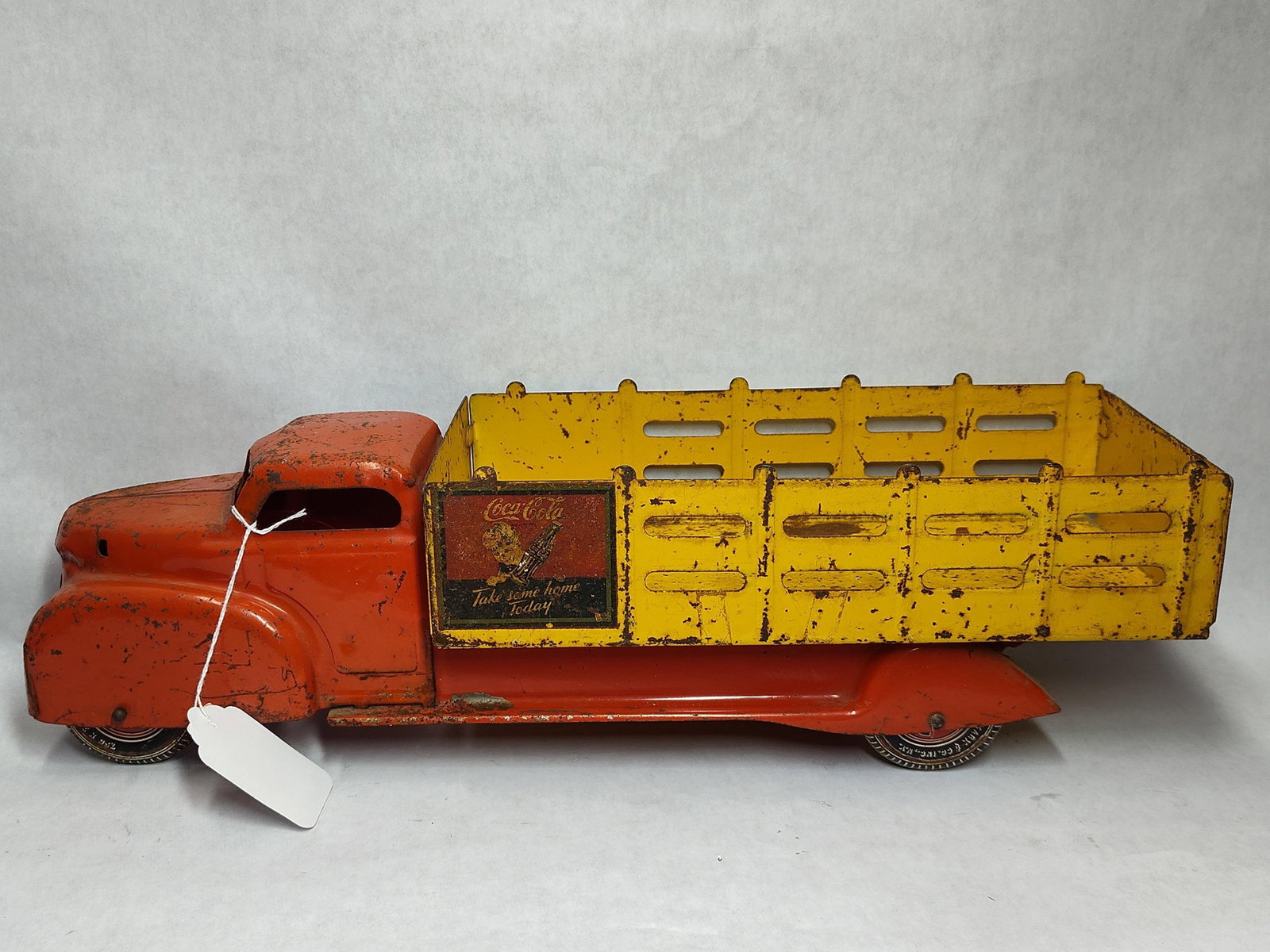 Marx Coca-Cola Sprite Boy Stake Bed Delivery Truck: A Coca-Cola delivery truck manufactured by Louis Marx and Co. The toy is constructed of pressed steel with a 1940s-style aerodynamic cab and chassis finished in orange-red paint. The vehicle features