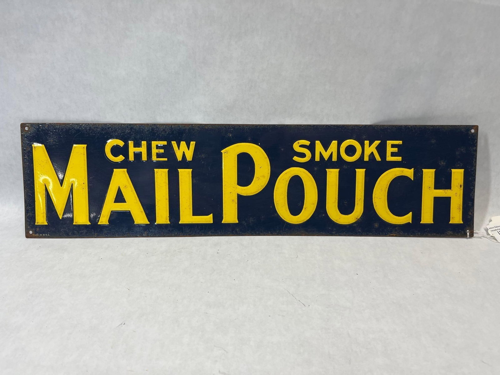 Mail Pouch Tobacco Embossed Metal Advertising Sign: A mid-20th century embossed metal advertising sign for Mail Pouch Tobacco. The rectangular sign features a dark blue enameled background with raised yellow lettering. The layout includes the word