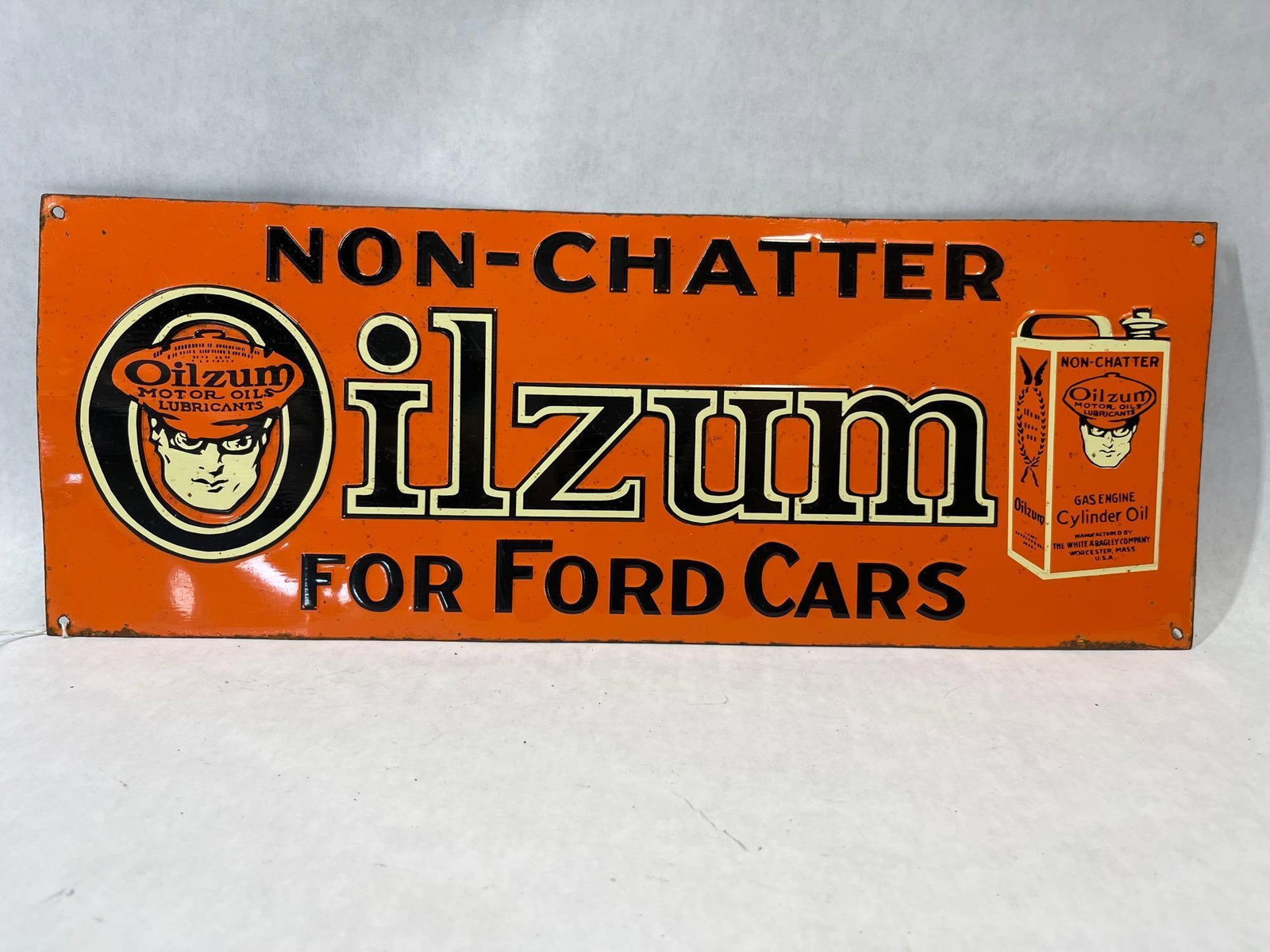 Oilzum Non-Chatter Ford Embossed Advertising Sign: Original embossed advertising sign for Oilzum Motor Oils and Lubricants, manufactured by The White & Bagley Company of Worcester, Massachusetts. The sign features sharp, high-relief embossing on the
