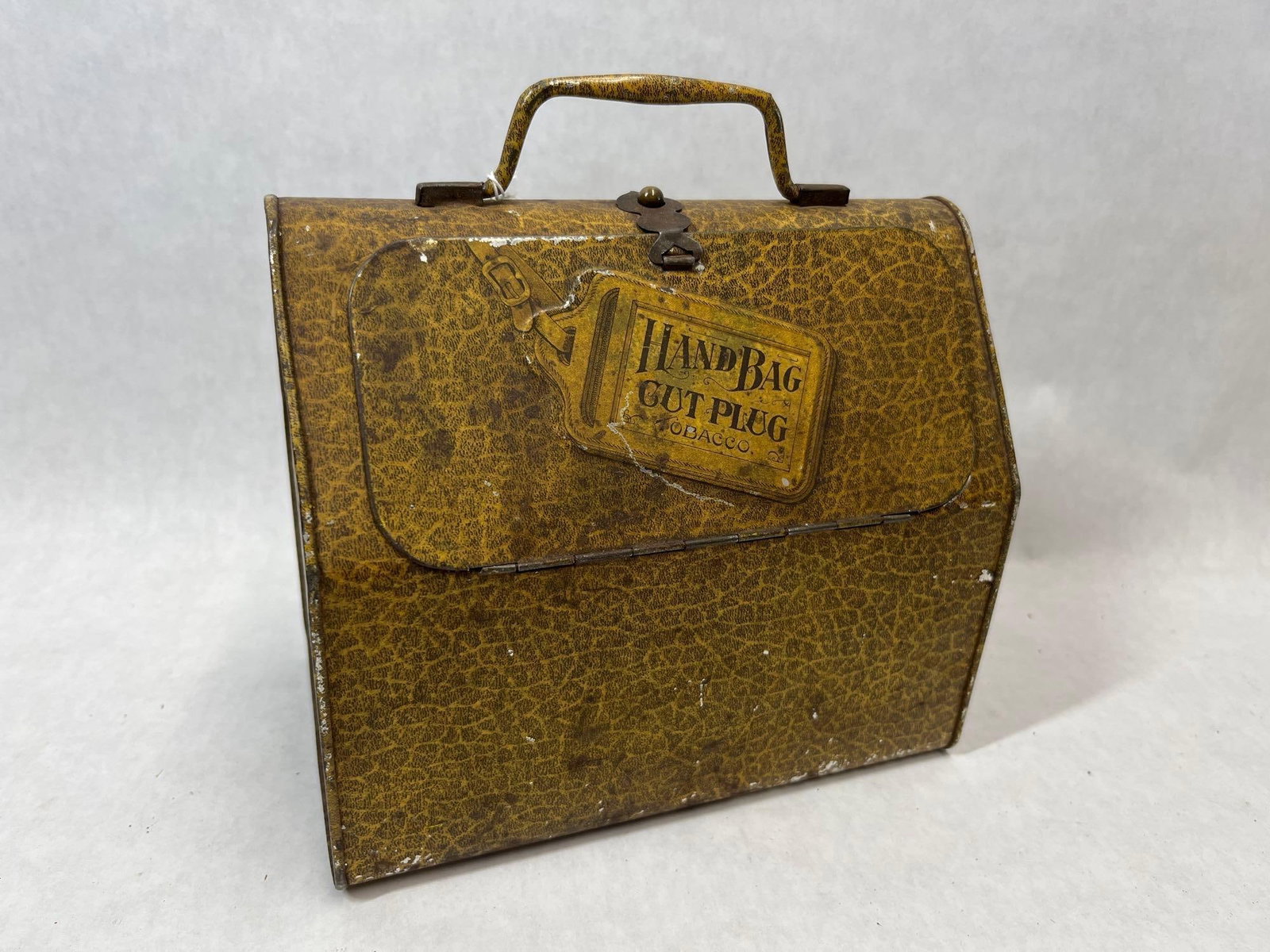 Larus & Brother Handbag Cut Plug Tobacco Tin: An early 20th-century lithographed tin tobacco container produced for the Larus and Brother Company of Richmond, Virginia. The tin is designed in the form of a small handbag or doctor's satchel,