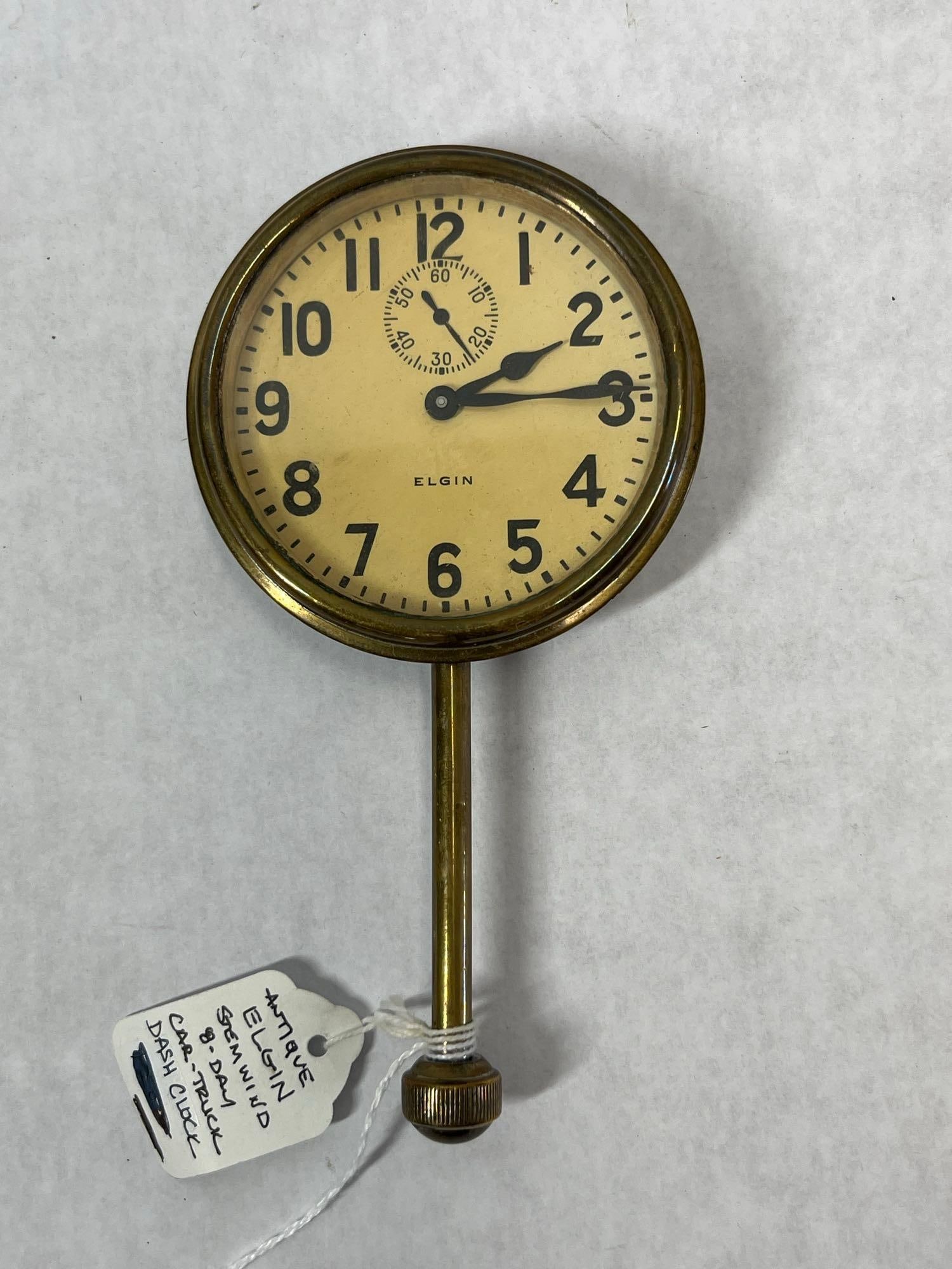 Elgin 8-Day Brass Automobile Dashboard Clock: This antique automotive dashboard clock was manufactured by the Elgin National Watch Co. around 1925. The timepiece features a round brass bezel and housing designed for dashboard mounting. It is