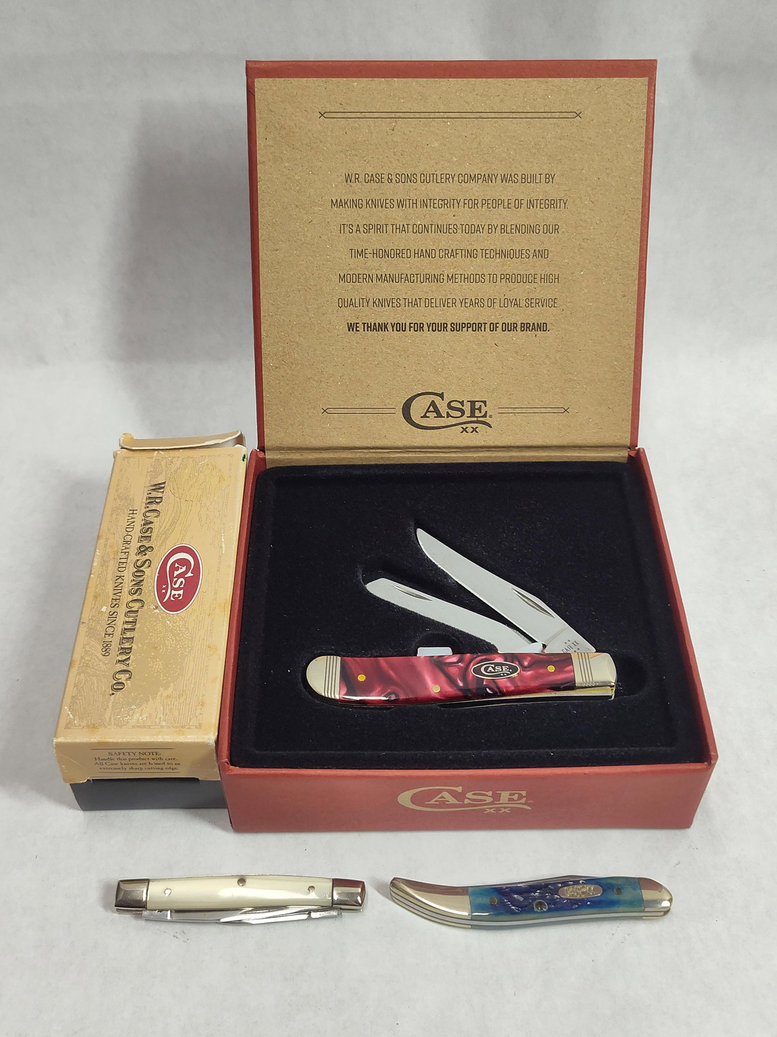 W.R. Case & Sons Trio of Folding Pocket Knives: This lot features three folding pocket knives manufactured by W.R. Case and Sons Cutlery Co., each accompanied by its original factory packaging. The first is a Trapper pattern pocket knife equipped