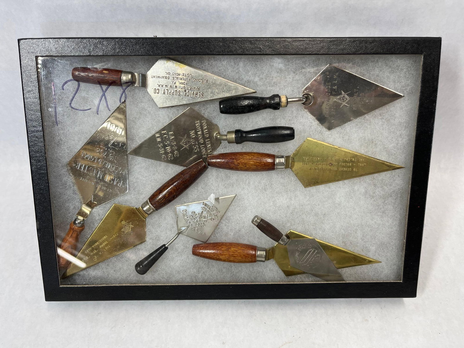 Set 9 Masonic & Advertising Miniature Trowels: A collection of nine miniature and commemorative trowels, including several Masonic ceremonial pieces and various industrial advertising items. The collection is professionally mounted in a