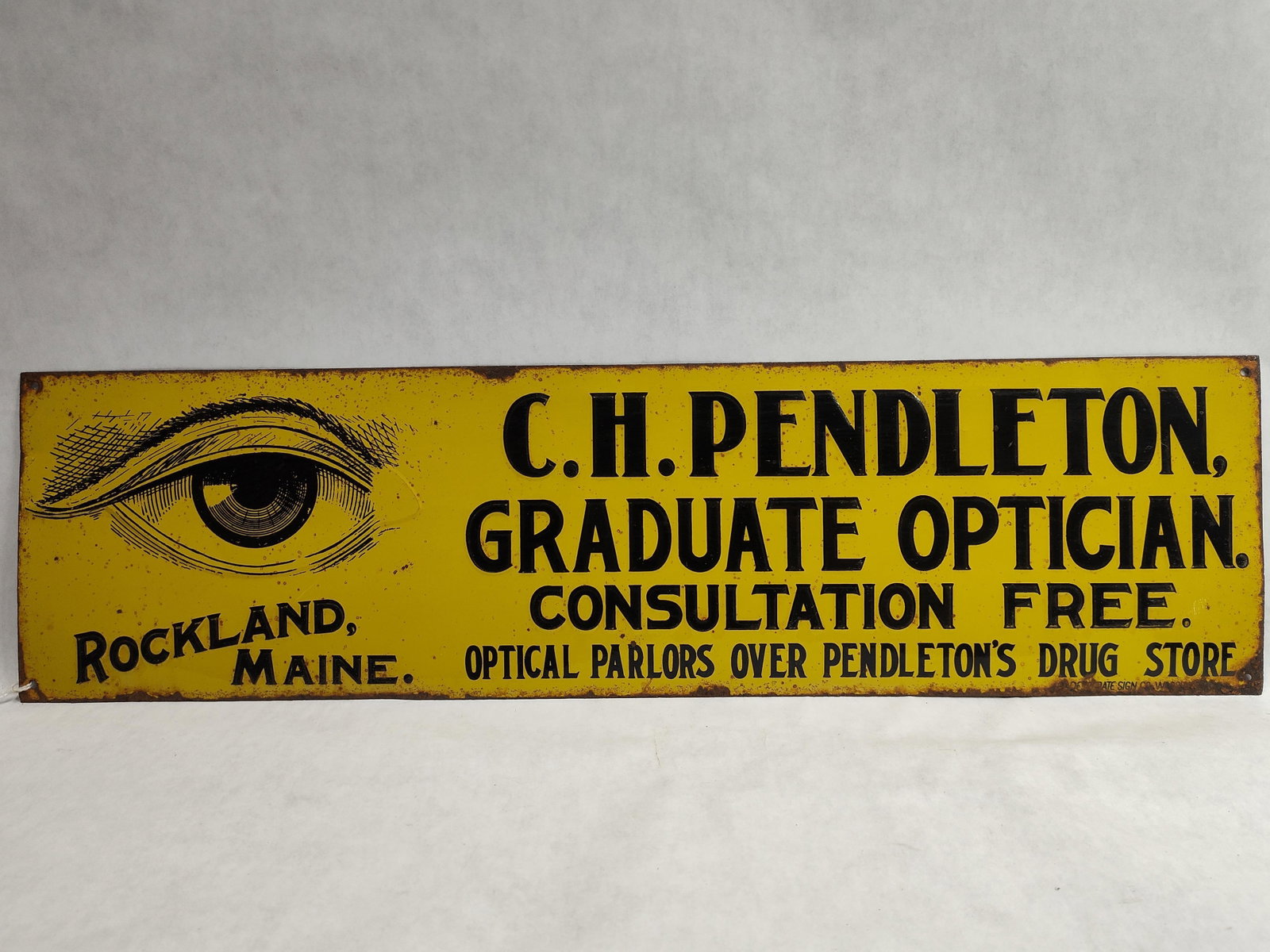 C.H. Pendleton Optician Rockland Embossed Tin Sign: This is a single-sided embossed metal trade sign for C.H. Pendleton, an optician formerly operating in Rockland, Maine. The sign is constructed from painted and embossed tin or light-gauge steel with