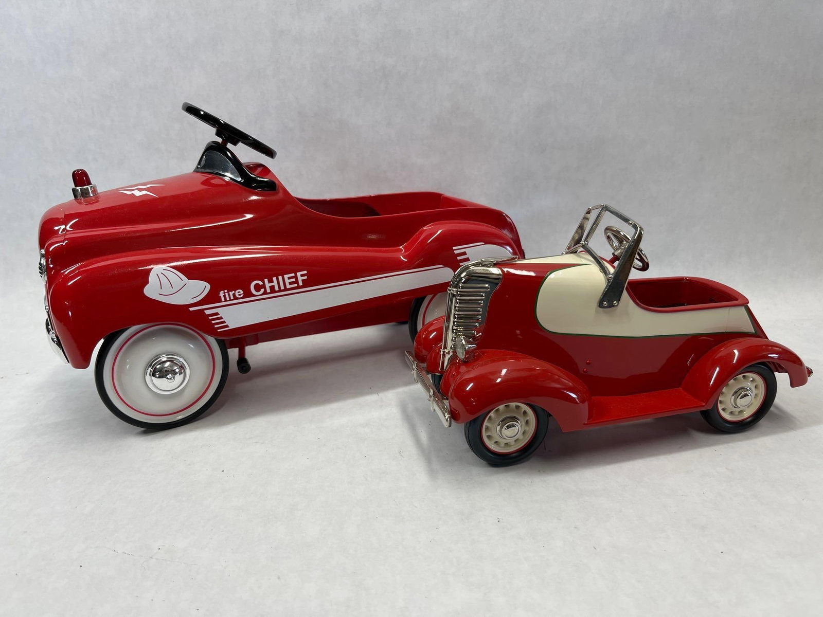 Xonex & Hallmark Scale Model Pedal Cars, Pair: This lot consists of two collector-quality scale-model pedal cars. The first is a Xonex Limited Edition Fire Chief model. It features a red die-cast metal body with white graphics including a