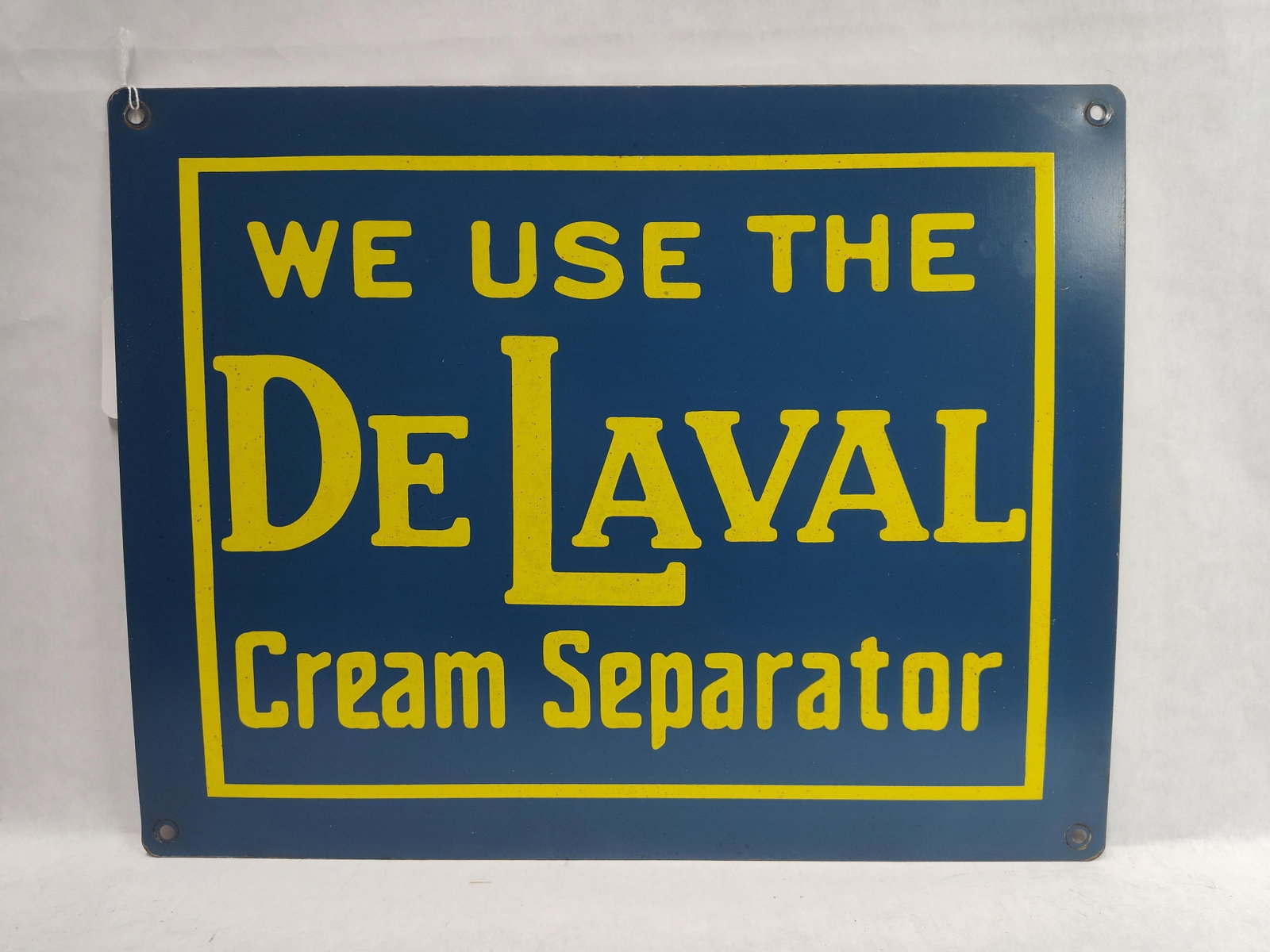 De Laval Cream Separator Porcelain Enamel Sign: A rectangular porcelain enamel advertising sign for De Laval Cream Separators. The sign features a dark blue ground with bold yellow lettering and a yellow linear border. The text is arranged in