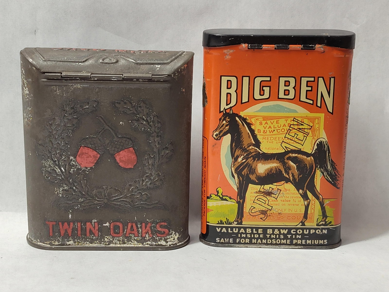 Twin Oaks & Big Ben American Tobacco Tins: This lot comprises two vertical pocket tobacco tins from prominent American brands. The first tin is a Twin Oaks Mixture tobacco container constructed of embossed tin with a dark, weathered finish.