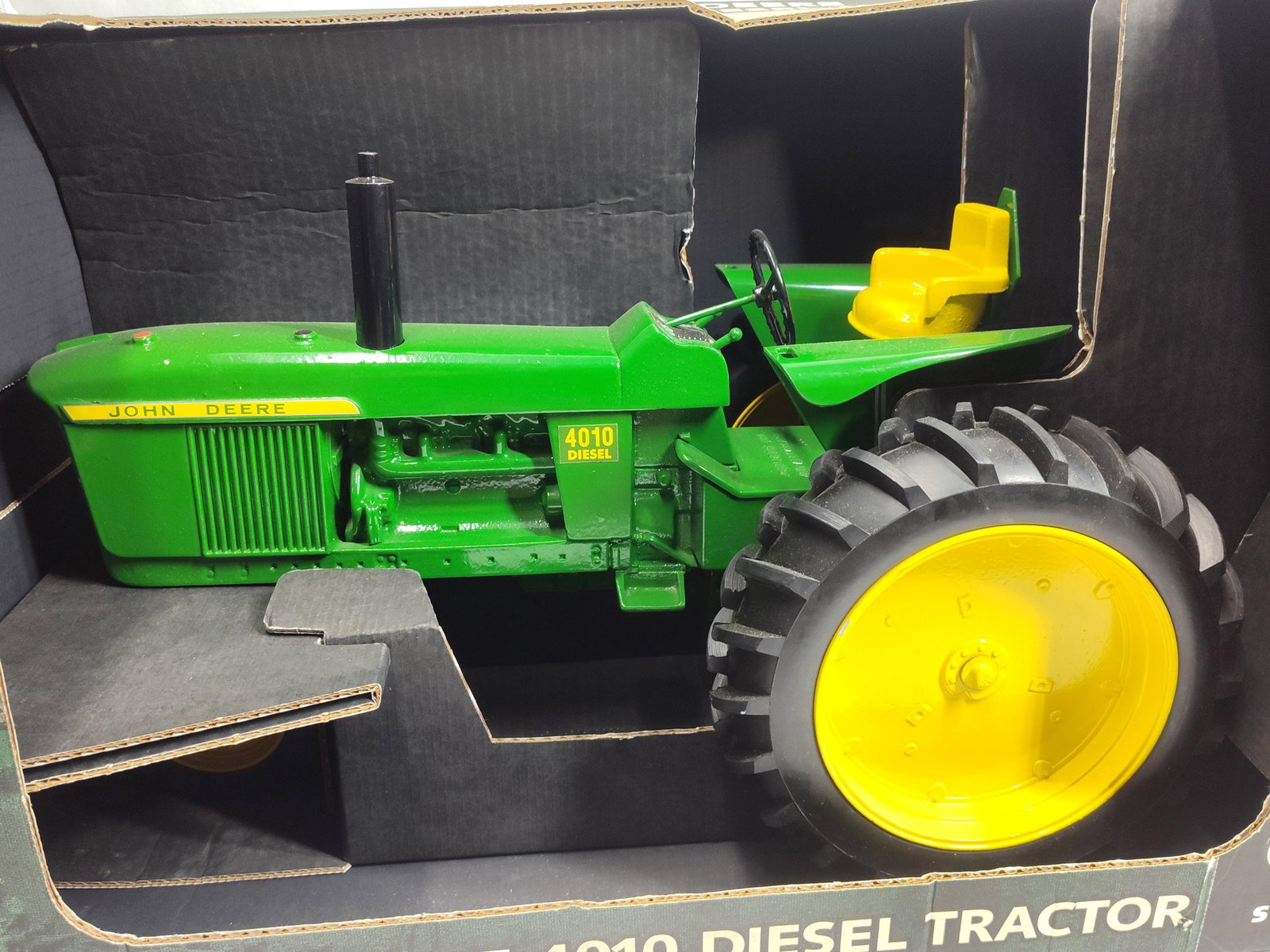 Ertl John Deere 1/8 4010 Diesel Tractor w/ Box: Produced by Ertl, this is a 1/8 scale model of a John Deere 4010 Diesel tractor. The model features a sandcast body and engine construction with black rubber tires mounted on yellow rims. The tractor 