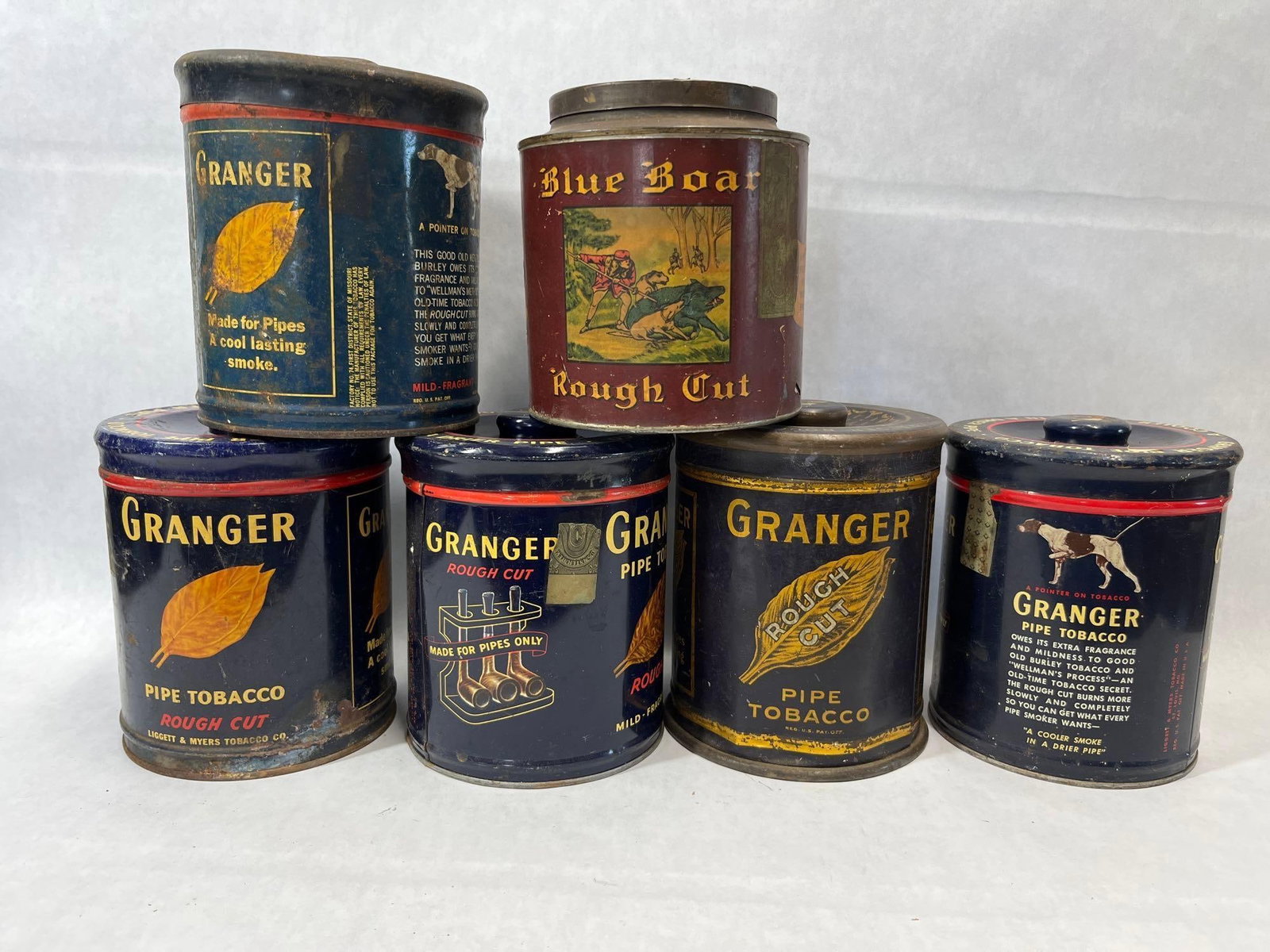 Set 6 Granger & Blue Boar Tobacco Humidor Tins: This lot consists of six lithographed metal pipe tobacco tins, including five from the Granger brand and one from the Blue Boar brand. The Granger tins were produced by the Liggett & Myers Tobacco