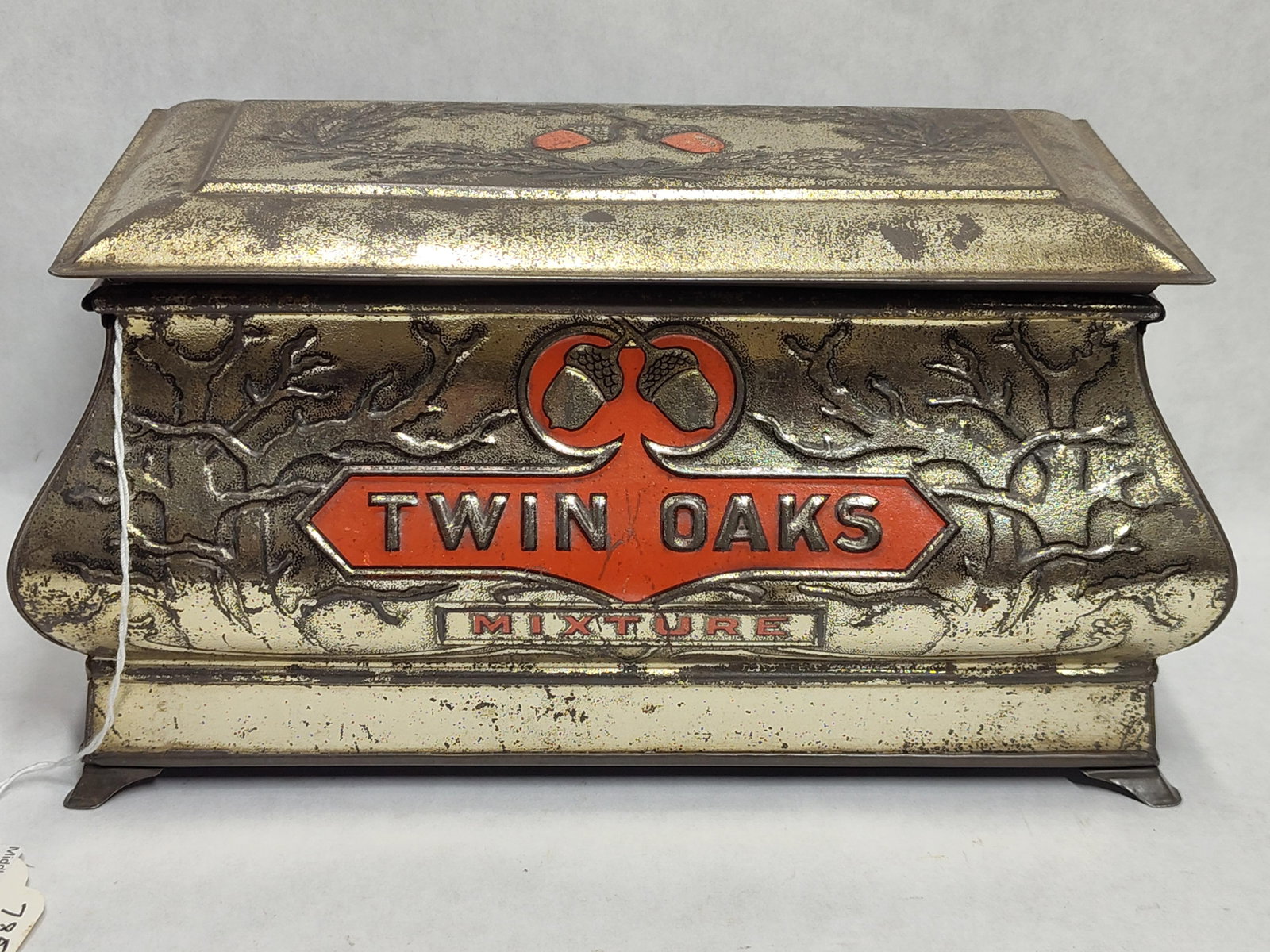 Twin Oaks Mixture Embossed Tobacco Humidor Tin: This is a Twin Oaks Mixture tobacco humidor tin, constructed in a decorative footed casket or chest form. The tin is made of lithographed and embossed metal. The front panel features a raised