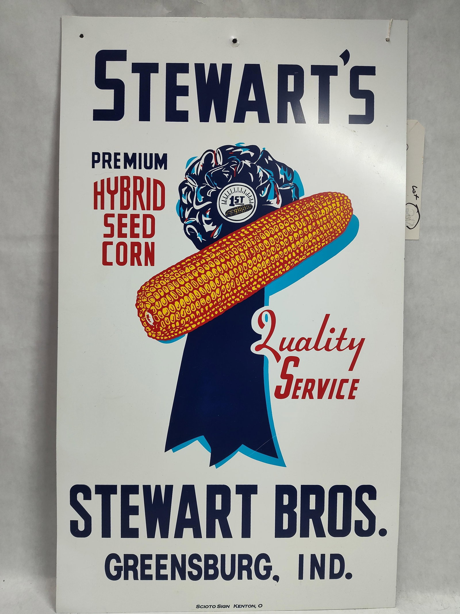 Stewart's Hybrid Seed Corn Tin Advertising Sign: A mid-20th century single-sided vertical tin advertising sign for Stewart's Premium Hybrid Seed Corn. The sign is constructed of lithographed metal with a white background and multi-colored graphics.