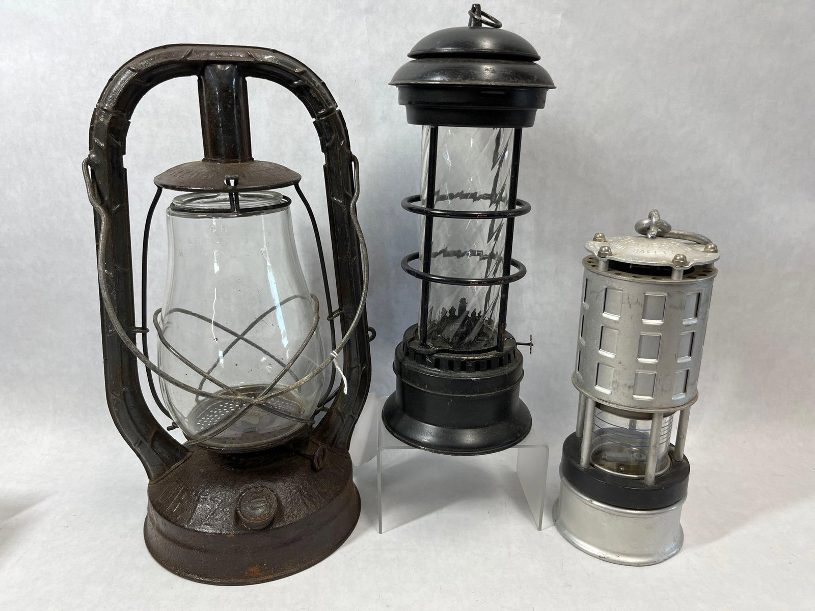 Dietz Monarch & Koehler No. 209 Lantern Trio: This lot features three distinct industrial and utility lanterns from the early to mid-20th century. The first item is an R.E. Dietz Company Monarch hot-blast tubular lantern. The steel body features
