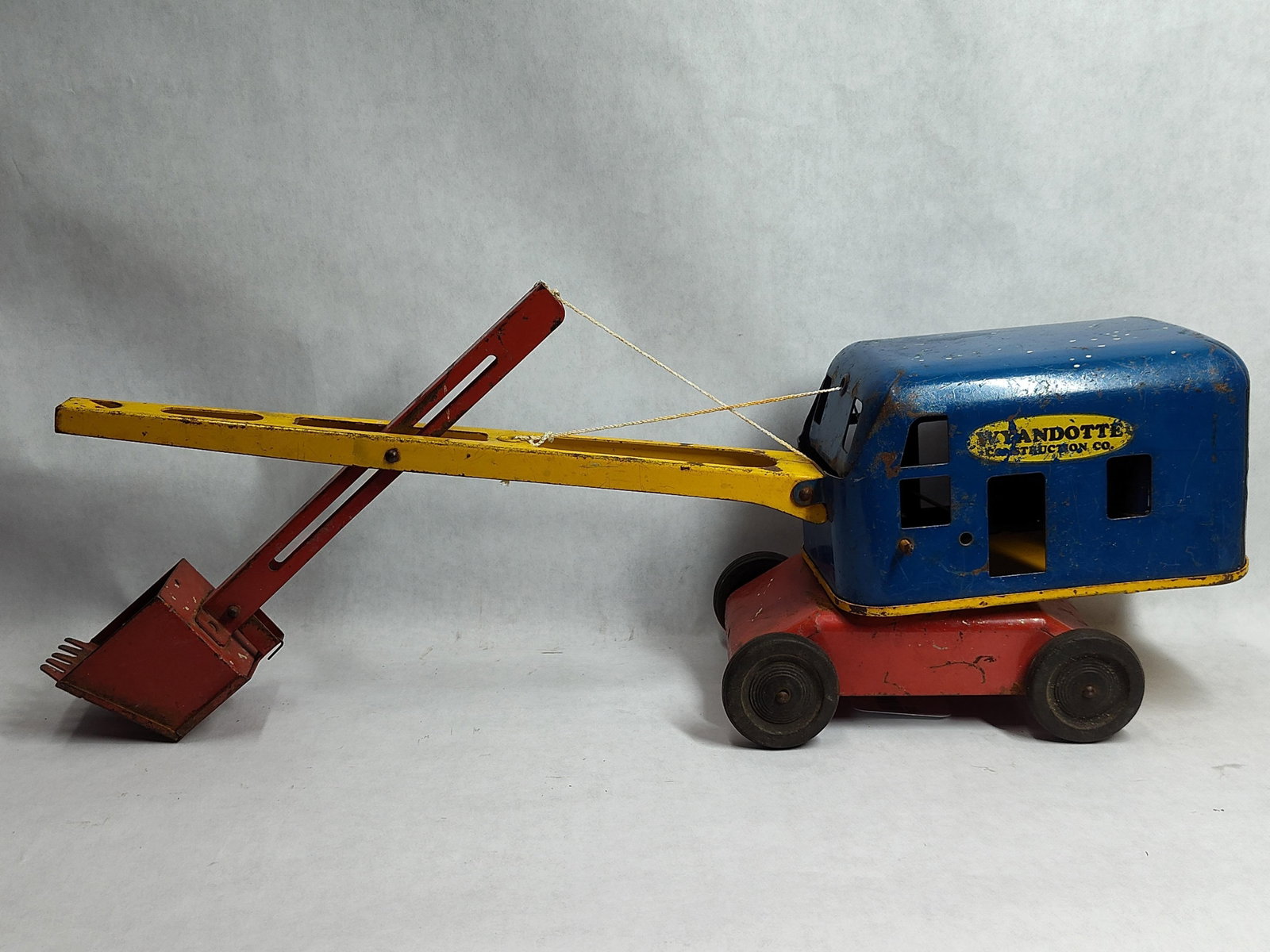 Wyandotte Construction Co. Toy Steam Shovel: This toy is a pressed steel steam shovel manufactured by Wyandotte Toys under the Wyandotte Construction Co. brand. The toy features a blue cab that rotates on a red chassis with four black rubber whe