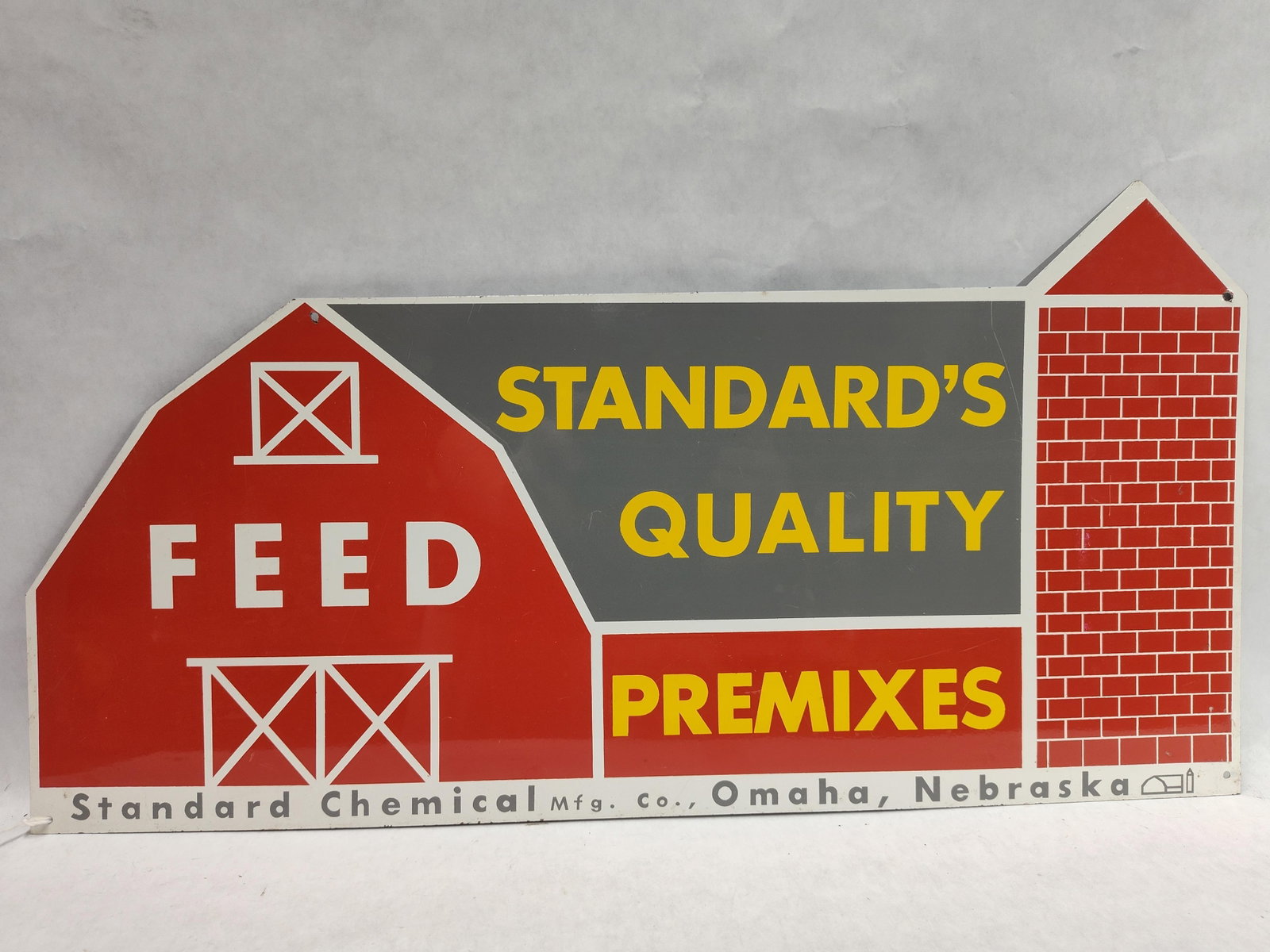 Standard Quality Feed Premixes Die-Cut Metal Sign: A die-cut painted metal advertising sign for the Standard Chemical Mfg. Co. of Omaha, Nebraska. The sign is shaped in the silhouette of a farm landscape, featuring a gambrel-roofed barn on the left