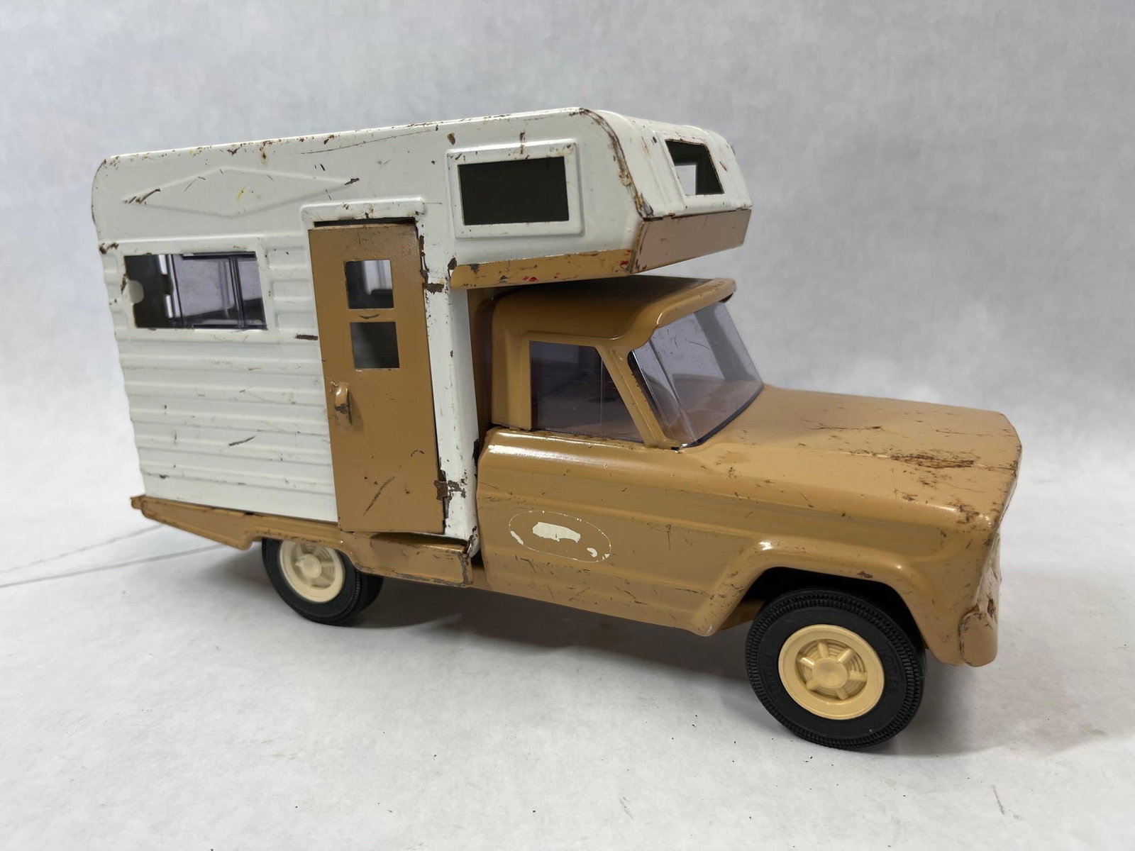 Tonka Pressed Steel Jeep Gladiator w/ Camper: This toy vehicle features a pressed steel pickup truck with an attached camper unit. The truck is modeled after the Jeep Gladiator casting used by the manufacturer. The truck body and camper door are 