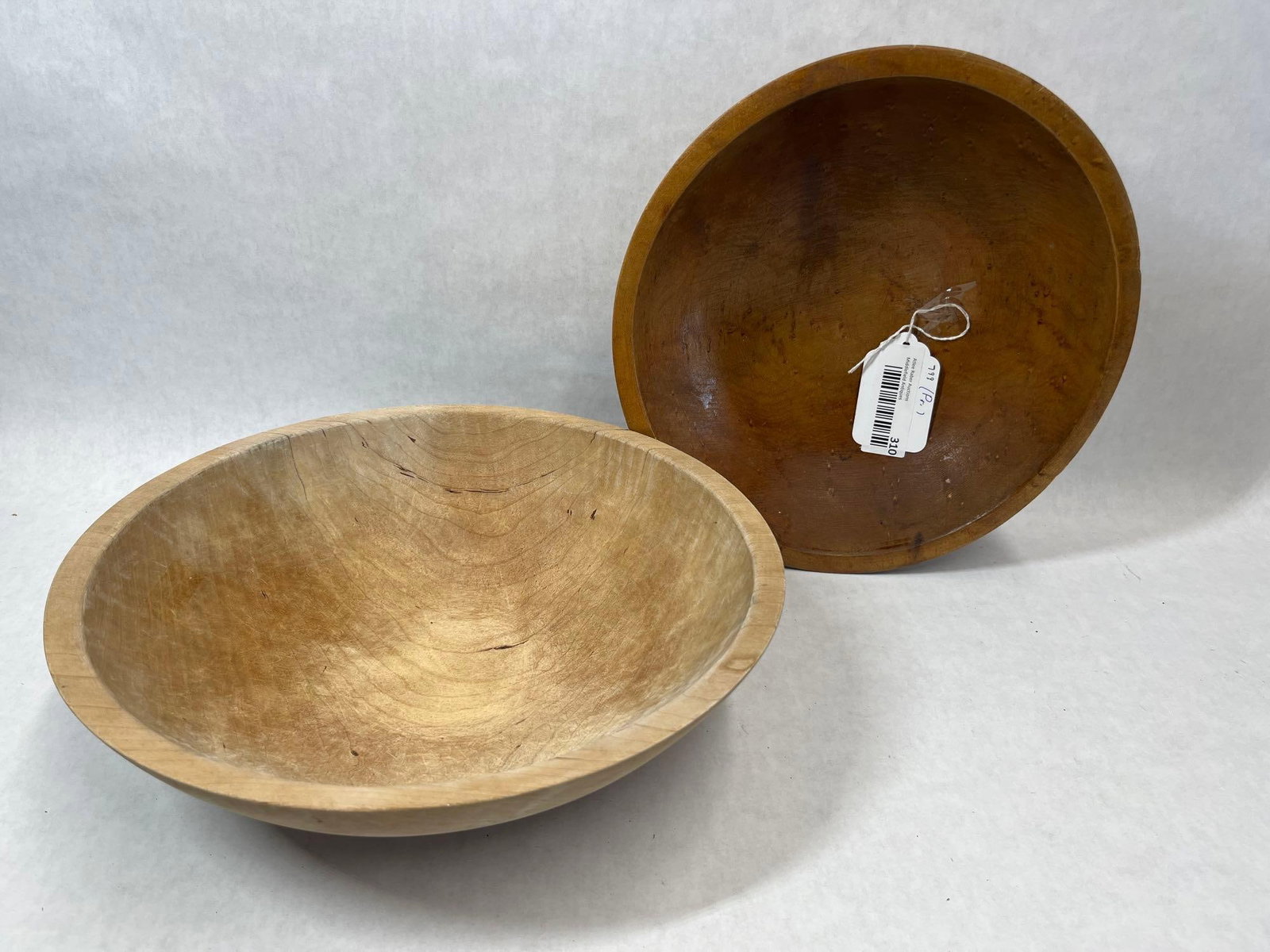 Pair American Munising Lathe-Turned Wood Bowls: A pair of American lathe-turned wooden bowls. The lot features one bowl in a natural finish that displays an incised maker mark for Munising on the base, identifying it as a product of the Munising