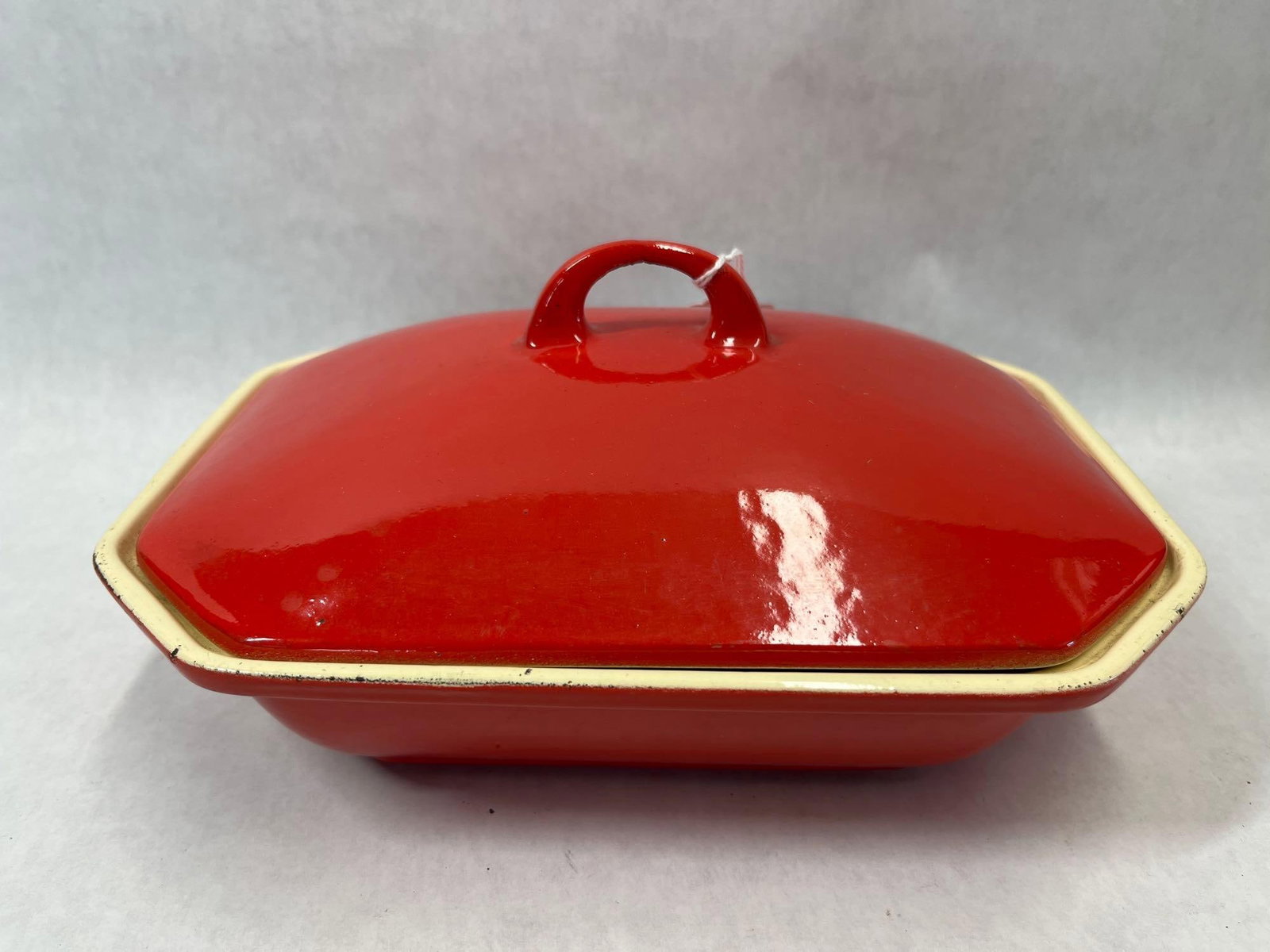 COPCO Red Rectangular Enamel Casserole Dish w/ Lid: This enameled cast iron casserole dish is a product of the Danish manufacturer COPCO. The piece features an octagonal, rectangular body with a conforming lid. The exterior is finished in a bright red