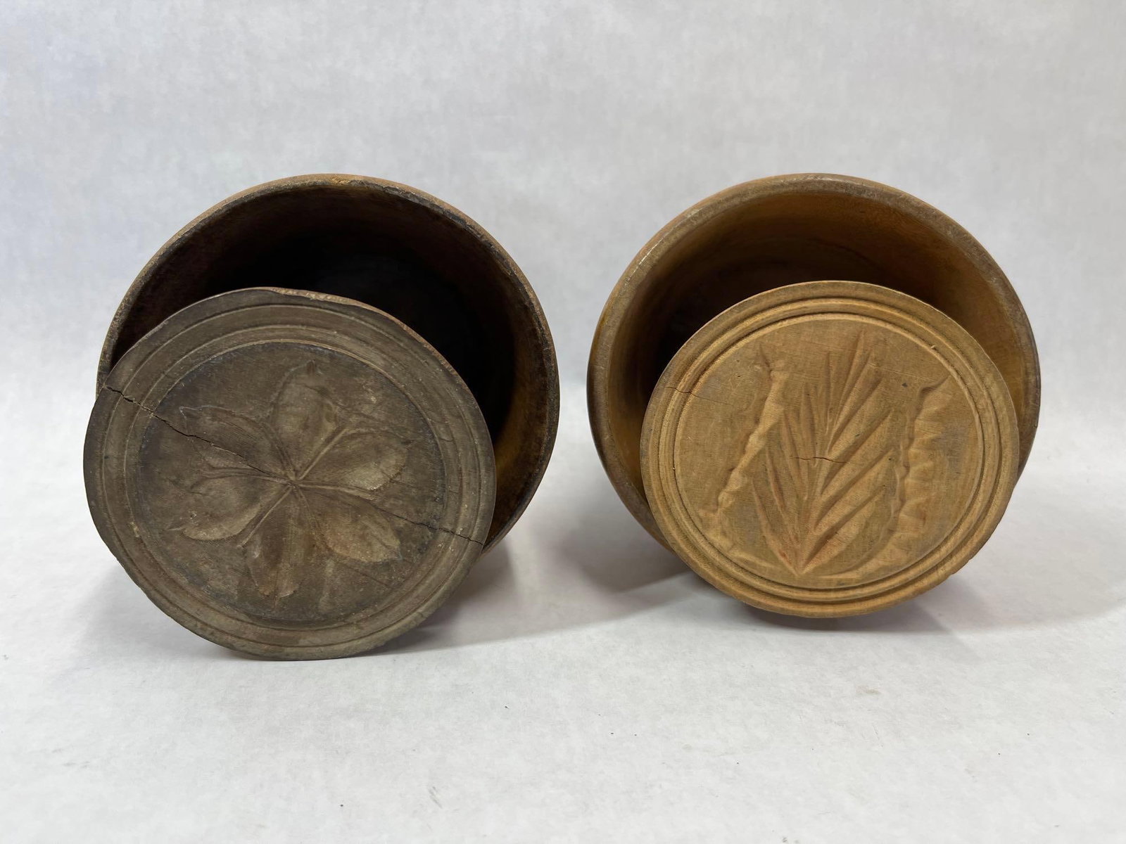 Pair American Wood Wheat & Rosette Butter Molds: This lot features a pair of antique American plunger-style butter molds constructed from lathe-turned hardwood. Each unit consists of a cylindrical sleeve with a flared base and a central plunger
