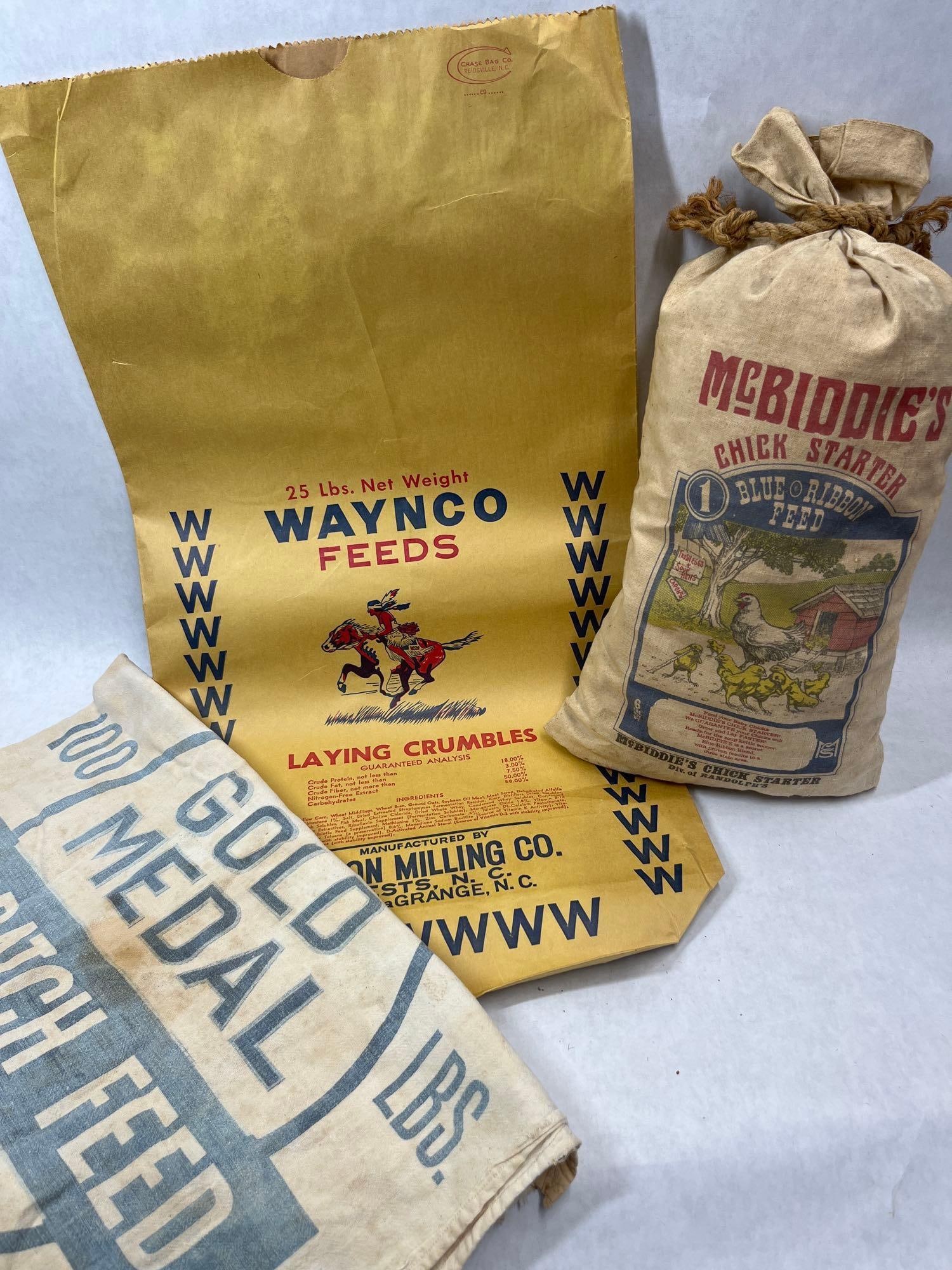 3 Waynco & General Mills Poultry Feed Bags: A collection of three poultry feed sacks comprising one paper bag and two cloth bags. The first item is a 25 lb. capacity paper bag for Waynco Feeds Laying Crumbles, manufactured by Eason Milling Co.
