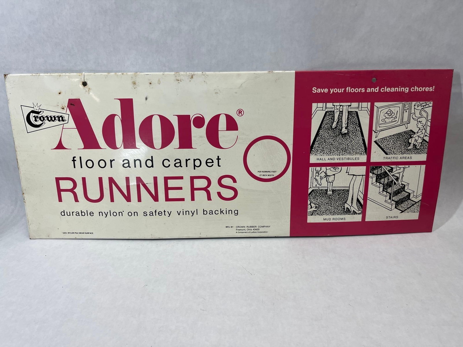 Crown Rubber Company Adore Floor and Carpet Runners Lithographed Metal Advertising Sign: A horizontal rectangular advertising sign for Adore floor and carpet runners, manufactured by the Crown Rubber Company of Fremont, Ohio. The sign is constructed of lithographed metal, likely tin or