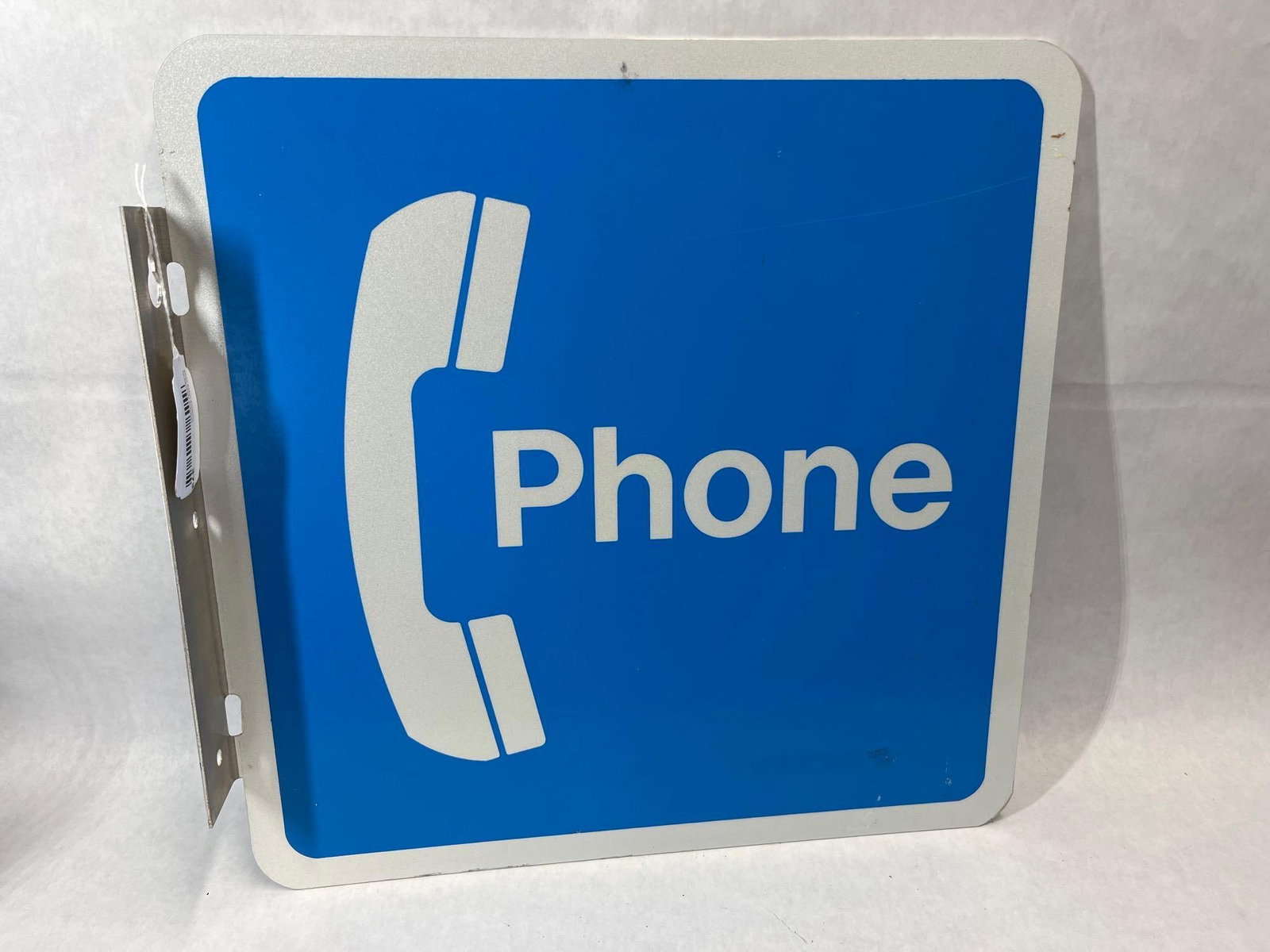 Metal Flange Public Telephone Sign: This is a double-sided metal flange sign used to identify the location of a public telephone. The sign features a blue square field with a white border. The graphics consist of a stylized white teleph