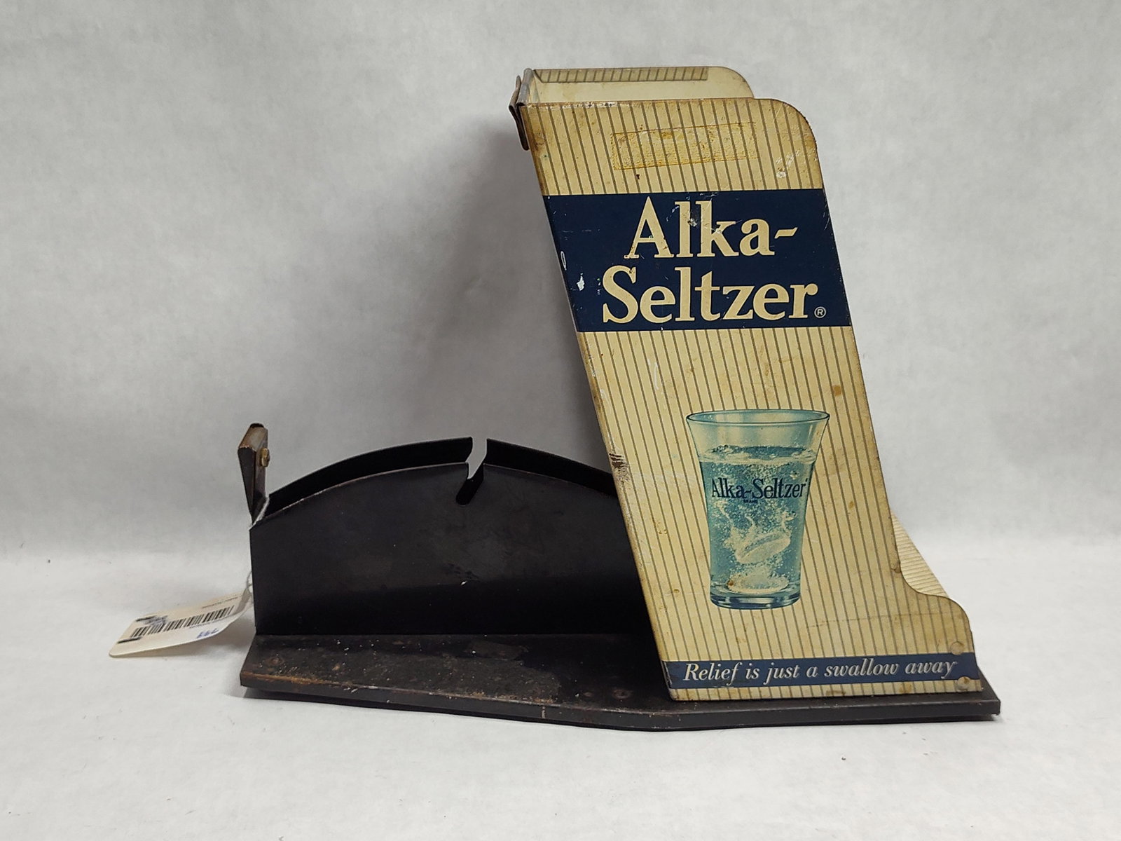 Alka-Seltzer Tin Litho Display & Tape Dispenser: This is a mid-20th-century point-of-sale countertop display for Alka-Seltzer. The unit is constructed from lithographed tin panels mounted on a heavy black-painted metal frame and base. The main