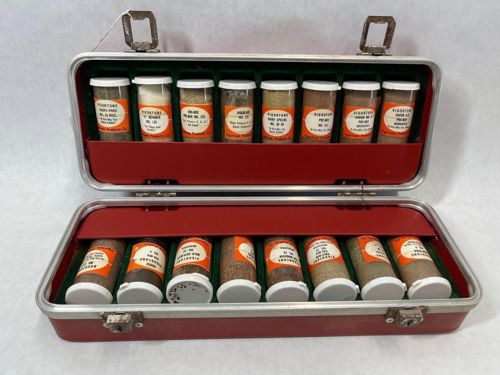 Vigortone Salesman Sample Kit in Red Case: A collection of animal feed supplement and medication samples from Vigortone Products Co., presented in their original salesman's carrying case. The case is constructed with a red textured vinyl