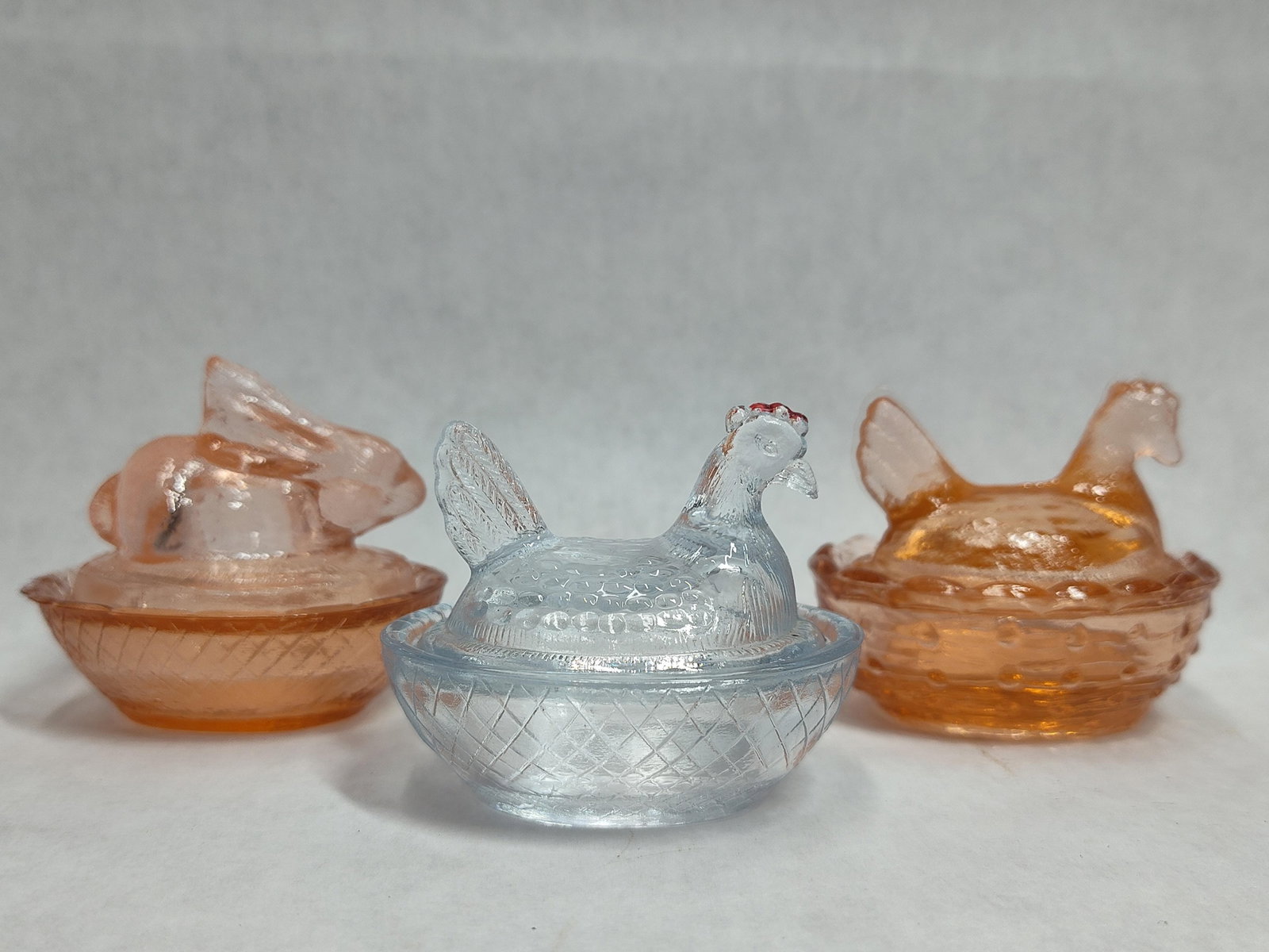 Trio Pressed Glass Covered Animal Dishes: This lot features three miniature pressed glass covered dishes in animal forms, commonly used as individual salt cellars or trinket boxes. The collection includes one reclining rabbit lid on a